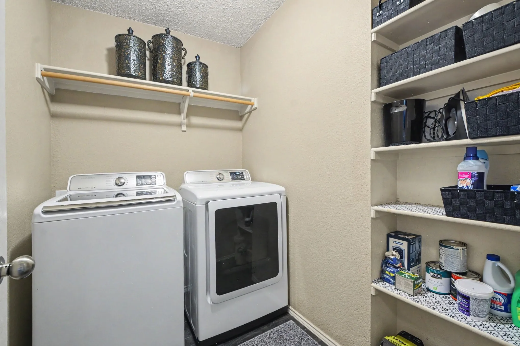 Dedicated laundry area featuring a white top-load washer, a white front-load dryer, an upper shelf with a clothing rod, and extensive built-in shelving