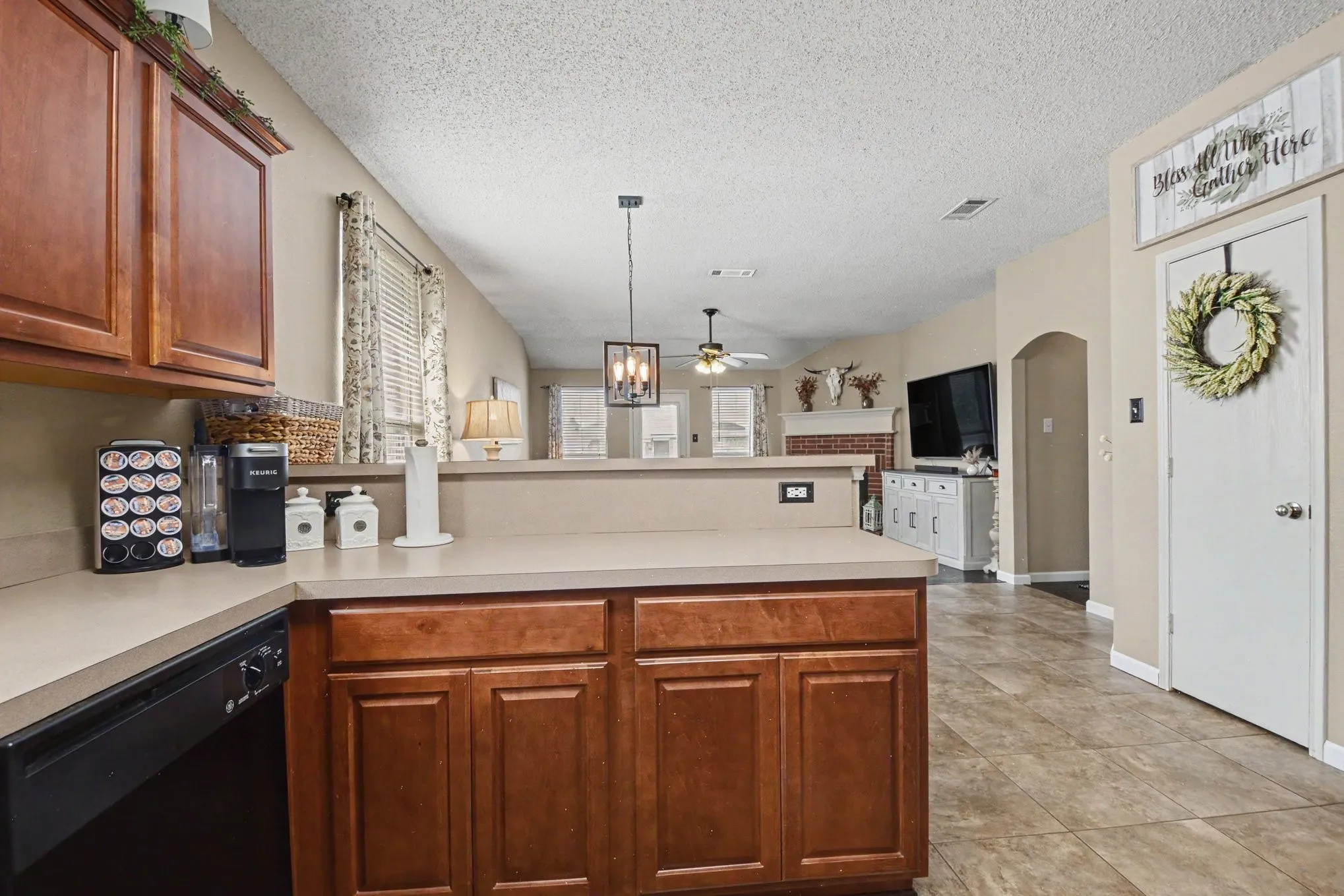 Kitchen featuring wood-finish cabinetry, solid surface countertops, and a black dishwasher