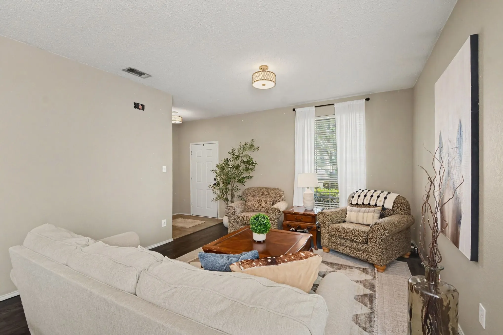 Living area featuring light neutral wall paint, dark wood-finish flooring, and a ceiling-mounted light fixture