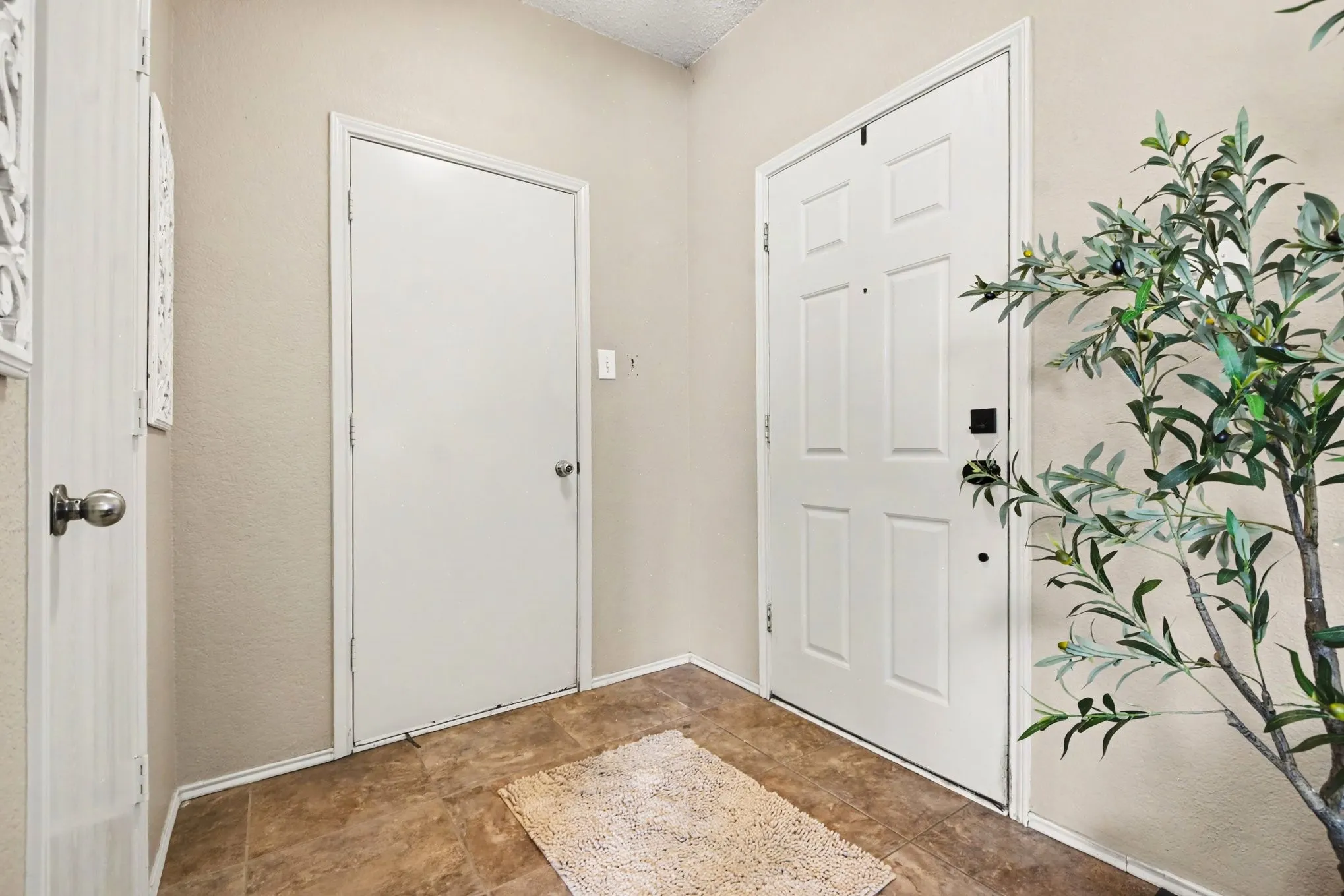 Entryway featuring light neutral wall paint, white trim, and rectangular floor tiles in a brown tone