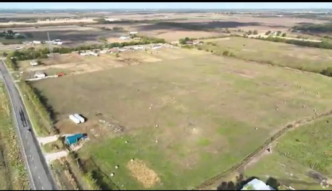 Expansive rural landscape featuring a paved road, scattered structures, and substantial open acreage