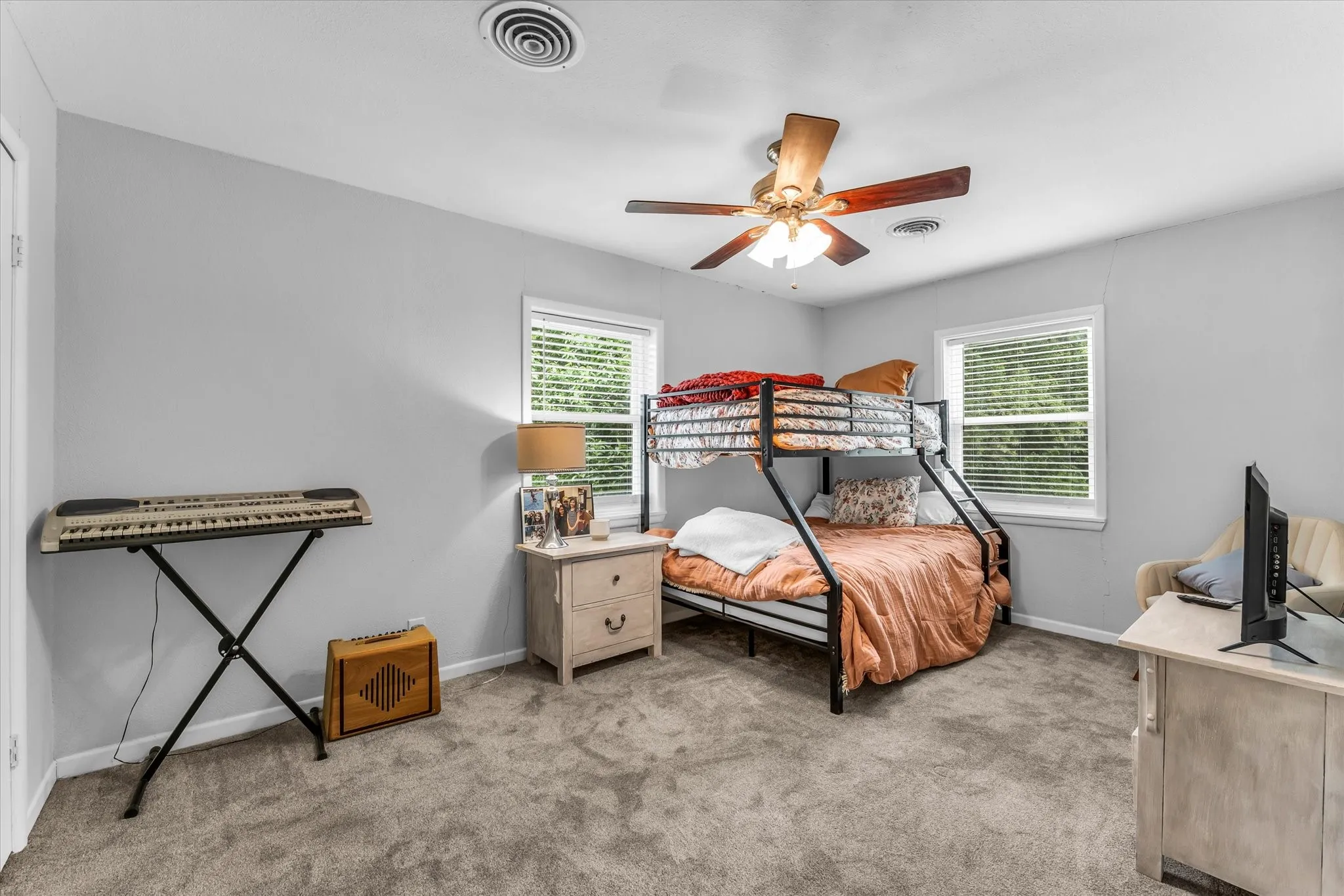 Carpeted room featuring light gray wall paint, two windows with blinds, a ceiling fan with integrated lighting, and a white door frame