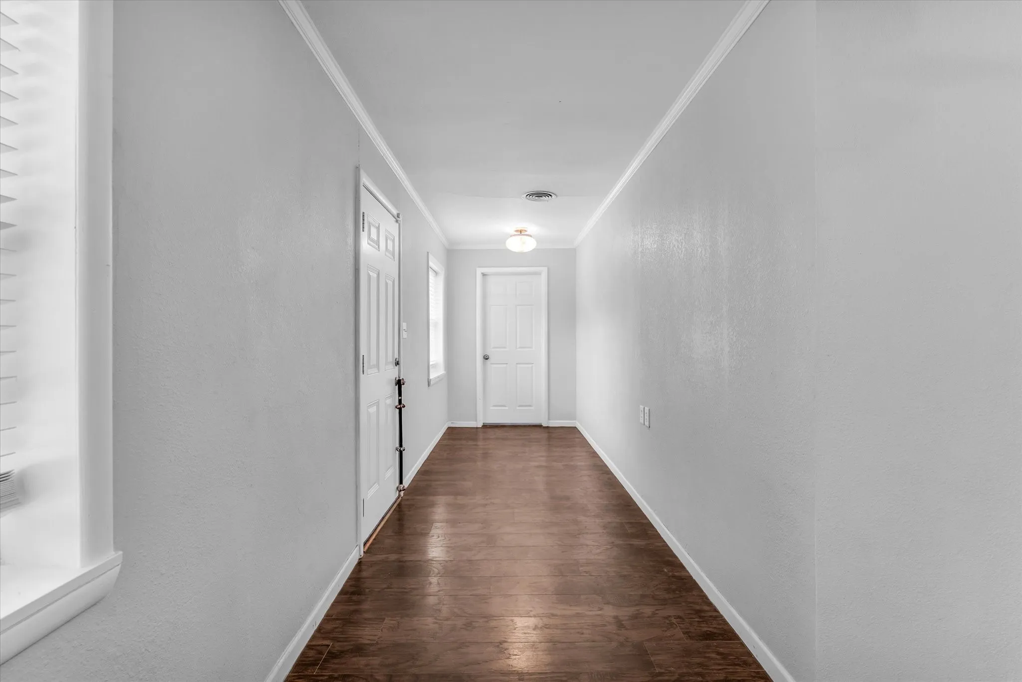 Hallway featuring wood-finish flooring, light gray walls, and white trim