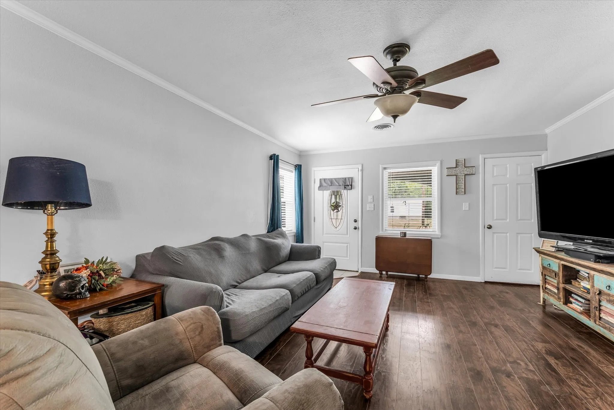 Living area featuring wood-finish flooring, light gray walls, and crown molding