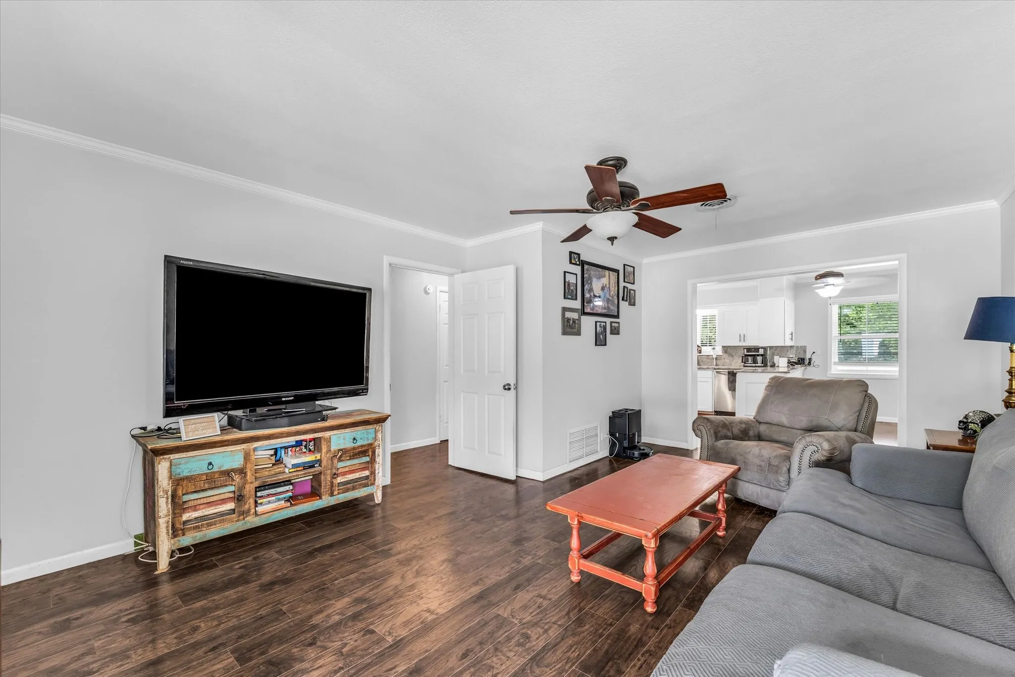 Living area featuring wood-finish flooring, light gray walls, and crown molding