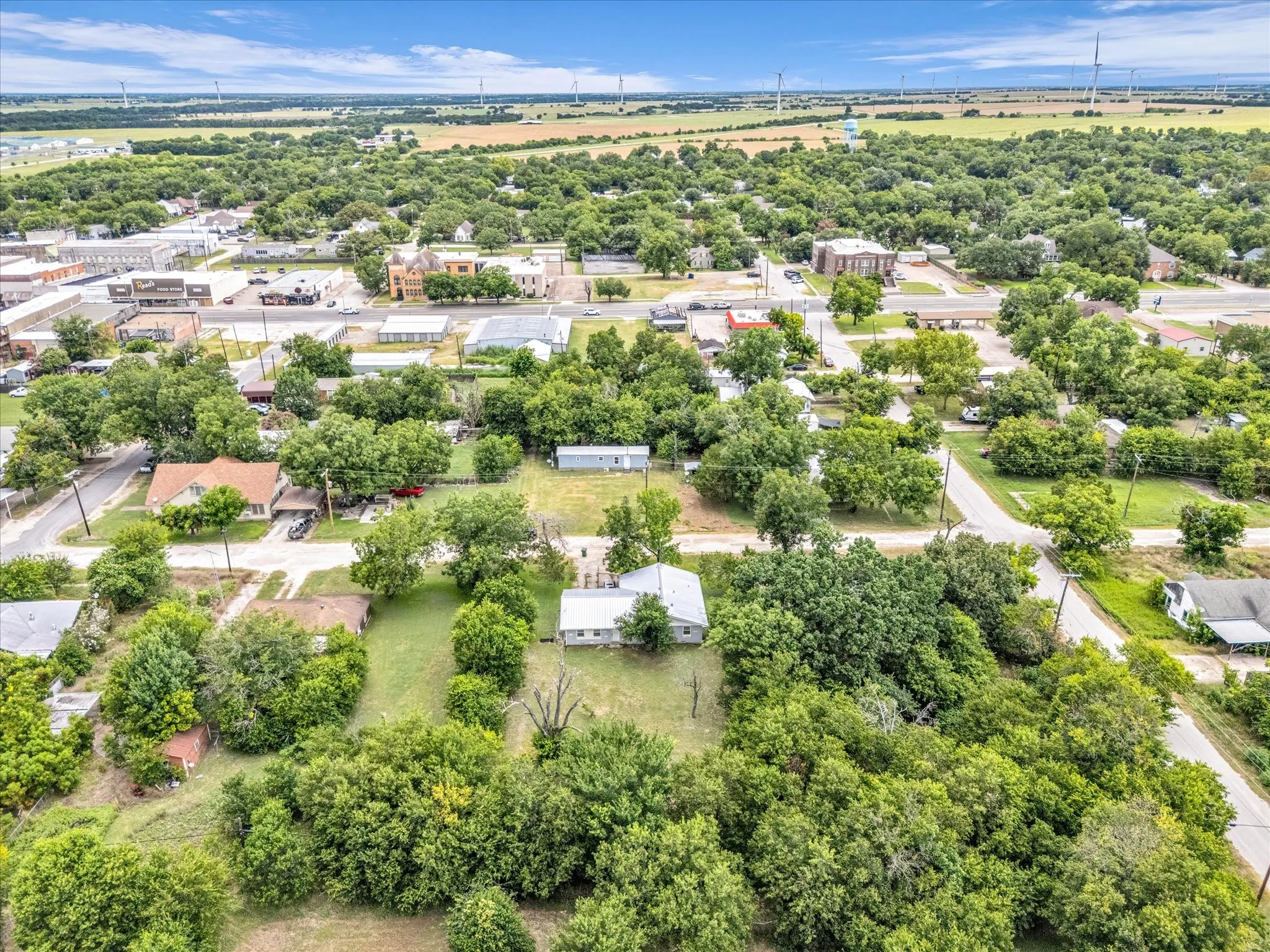 Aerial perspective showcasing a residential area with established trees and surrounding open fields