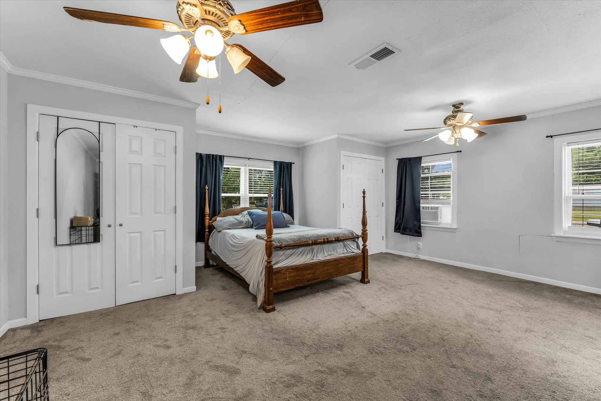 Spacious room featuring neutral carpet flooring, light gray walls, and white crown molding