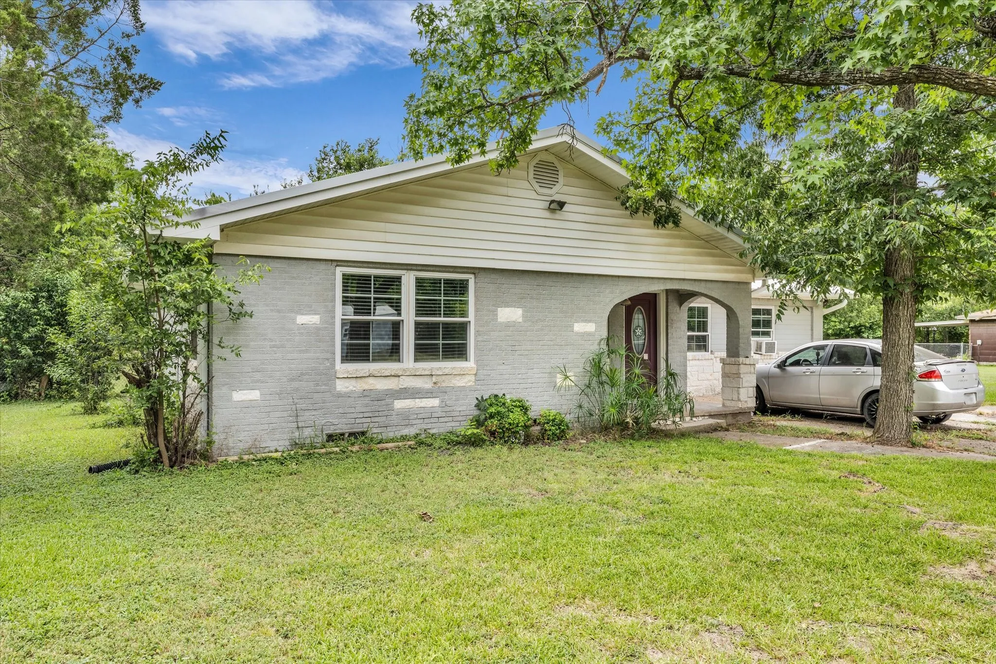 Single-story residence featuring a gray brick exterior with white siding accents and a covered front porch