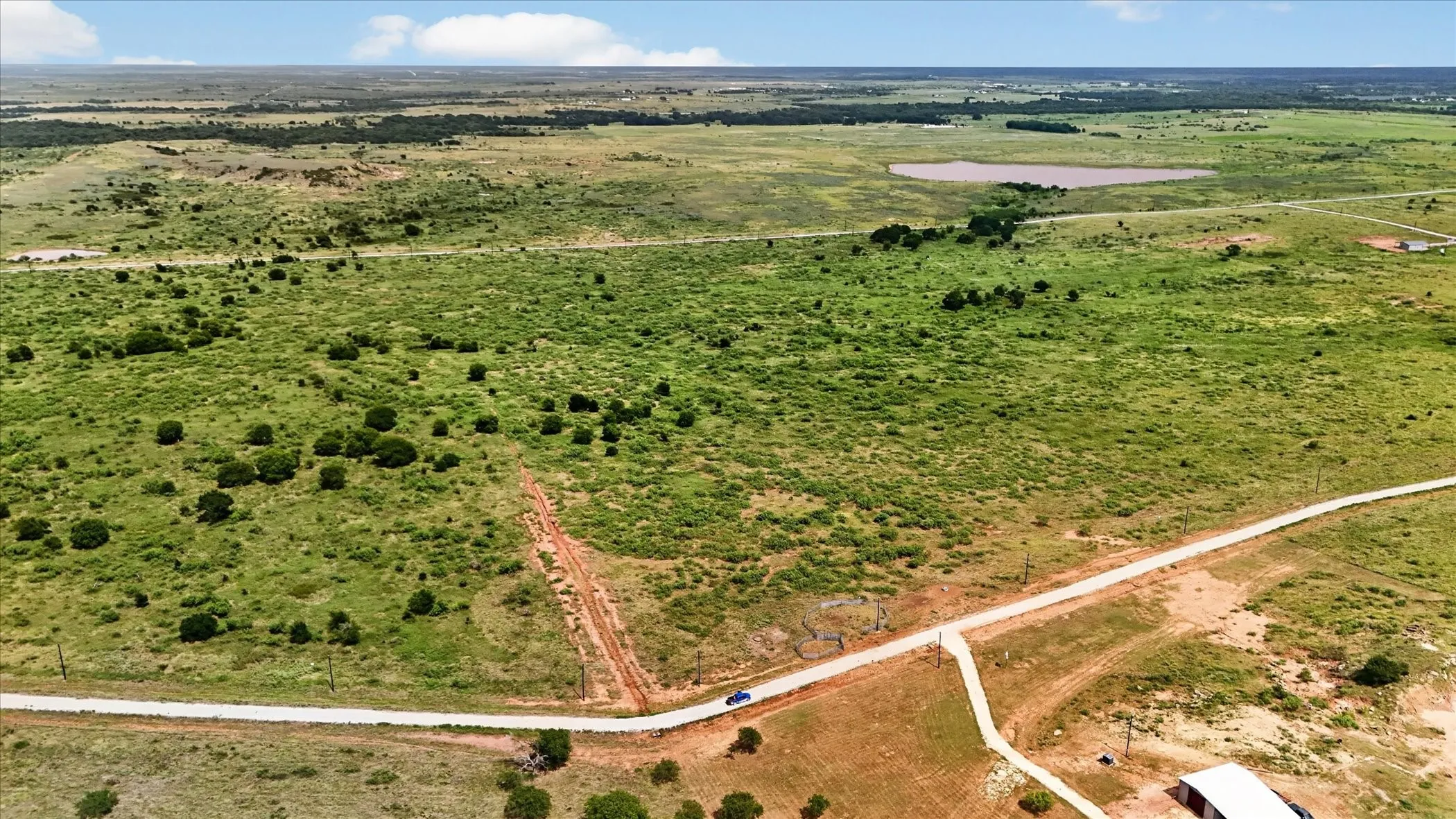 Expansive acreage featuring natural vegetation, scattered trees, and a visible roadway