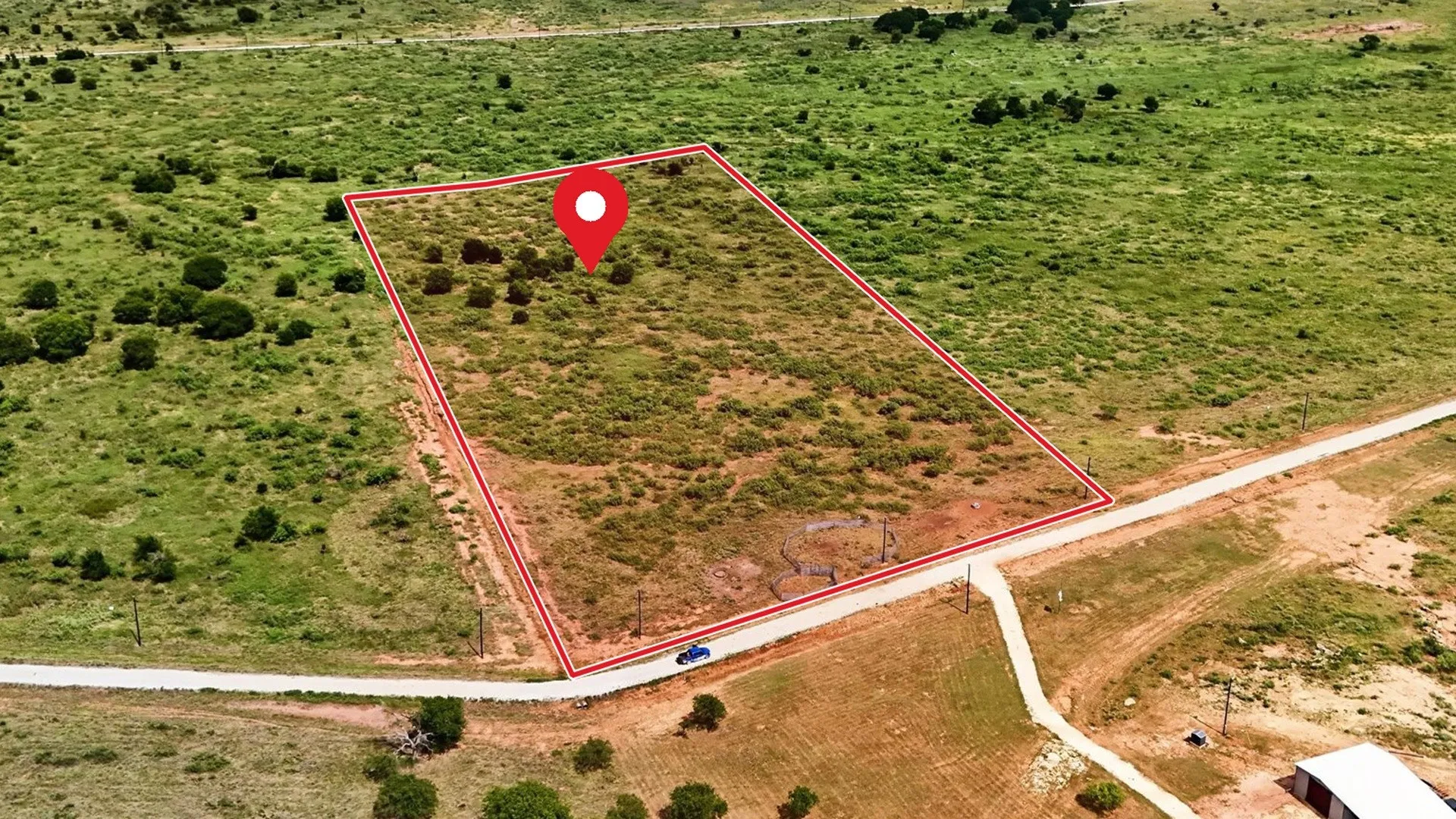 Expansive land parcel with clear boundary lines, featuring diverse natural vegetation and direct road frontage