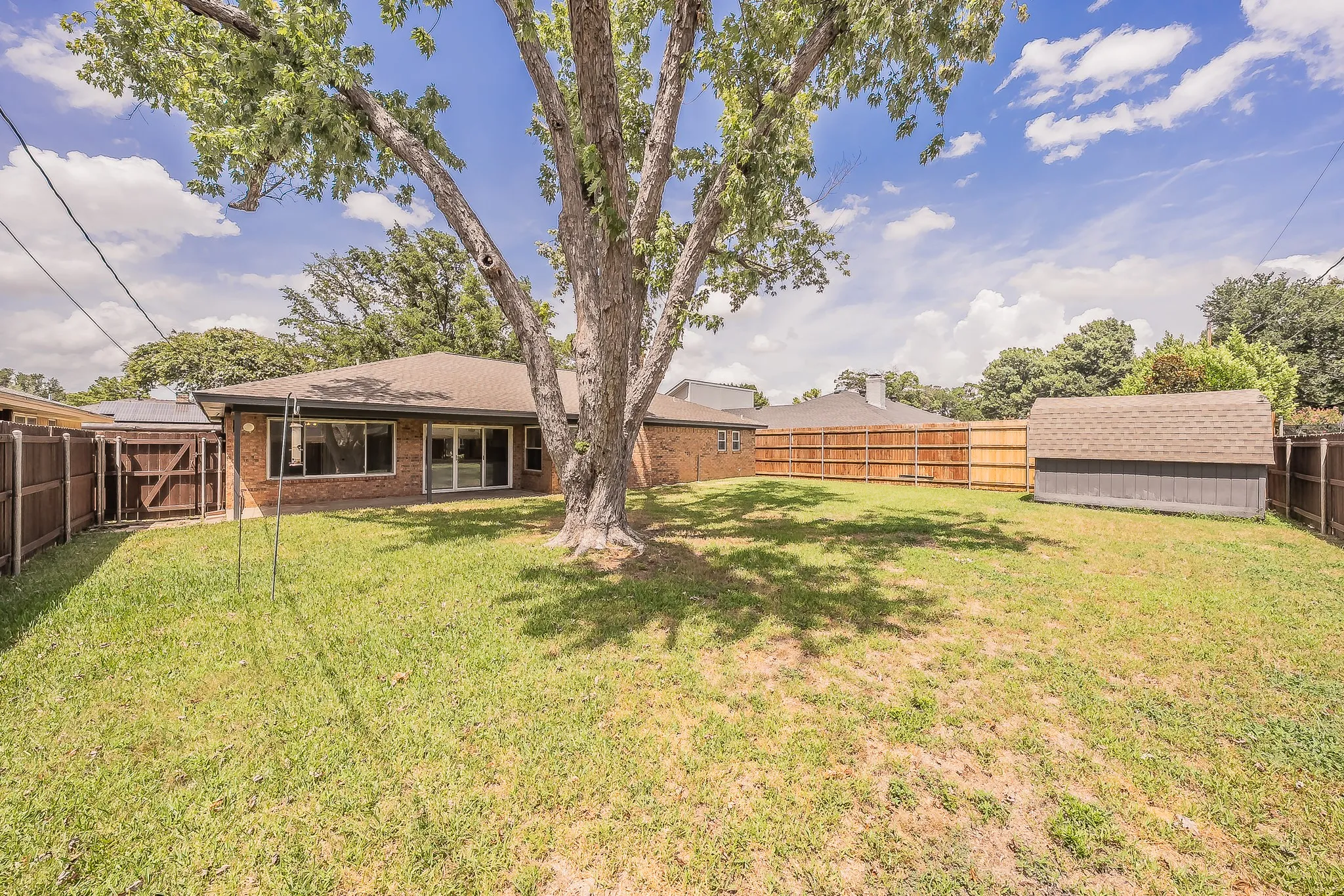 Large backyard with a storage shed that has electricity.