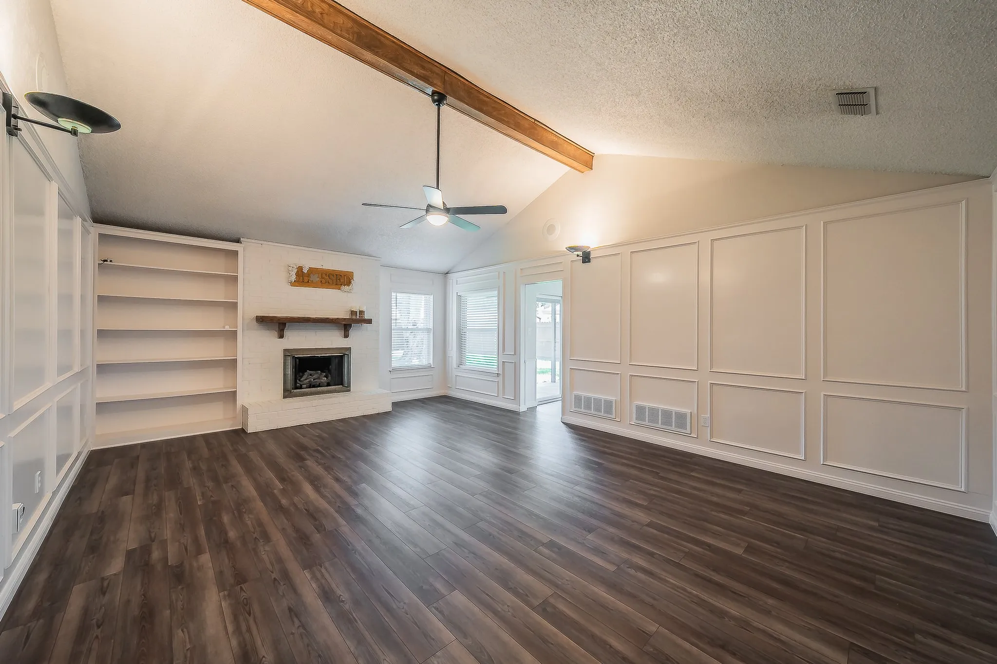 Spacious livng area with wood burning fire place and bulit in shelving .