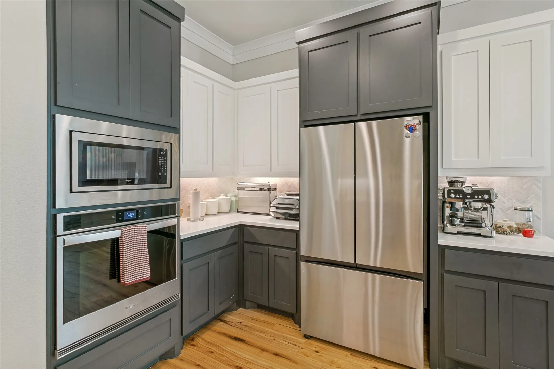 The kitchen features quartz countertops, pot-filler over the stove, herringbone backsplash, recessed and decorative lighting, additional seating at the bar