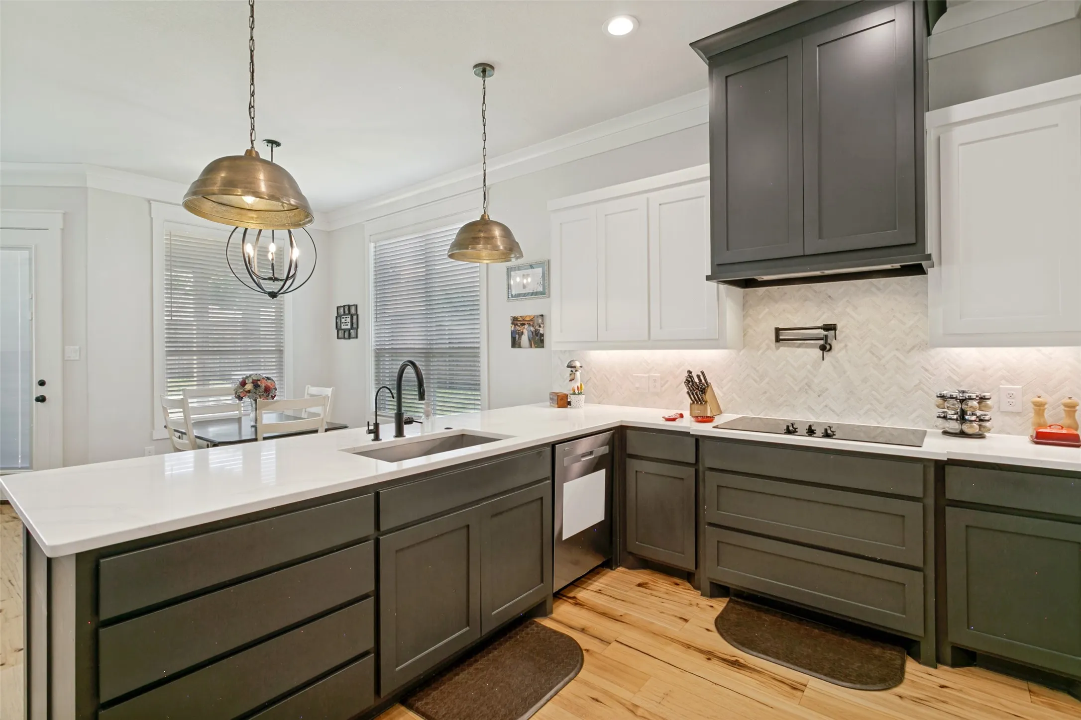 The kitchen features quartz countertops, pot-filler over the stove, herringbone backsplash, recessed and decorative lighting, additional seating at the bar