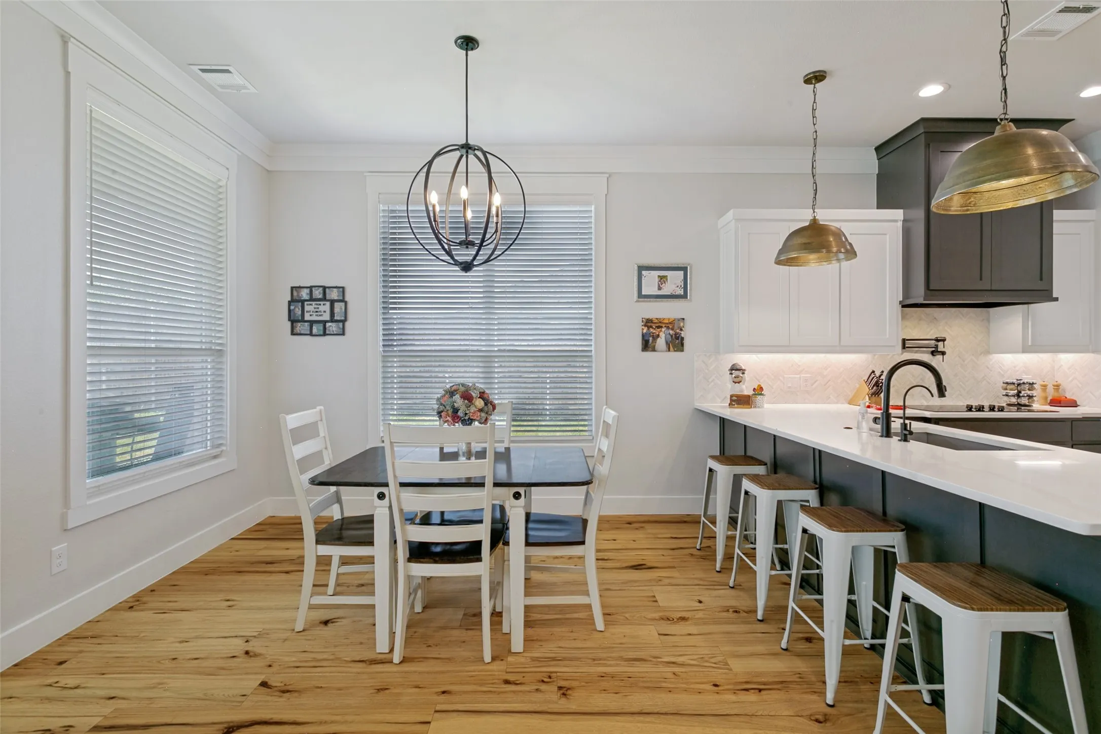 The kitchen features quartz countertops, pot-filler over the stove, herringbone backsplash, recessed and decorative lighting, additional seating at the bar