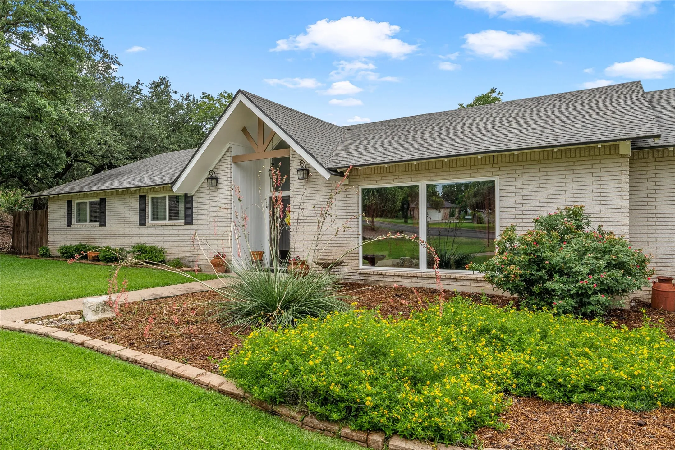 White brick exterior with a prominent gabled entry featuring natural wood accents