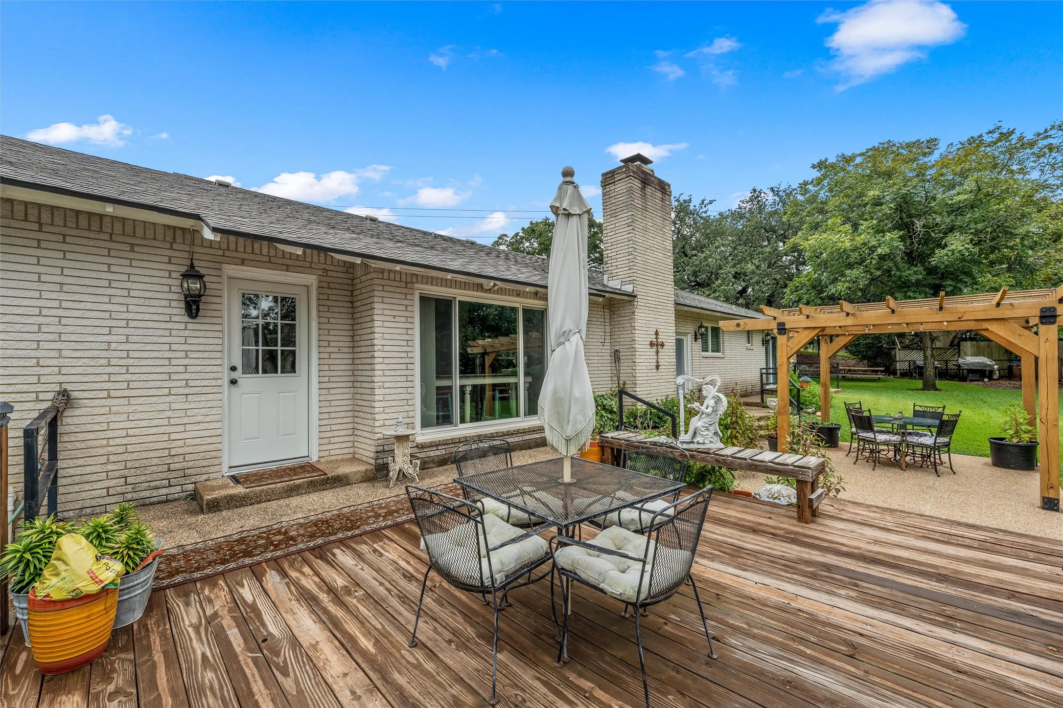 Expansive outdoor living area featuring a wood-finish deck, a gravel patio, and a wood pergola