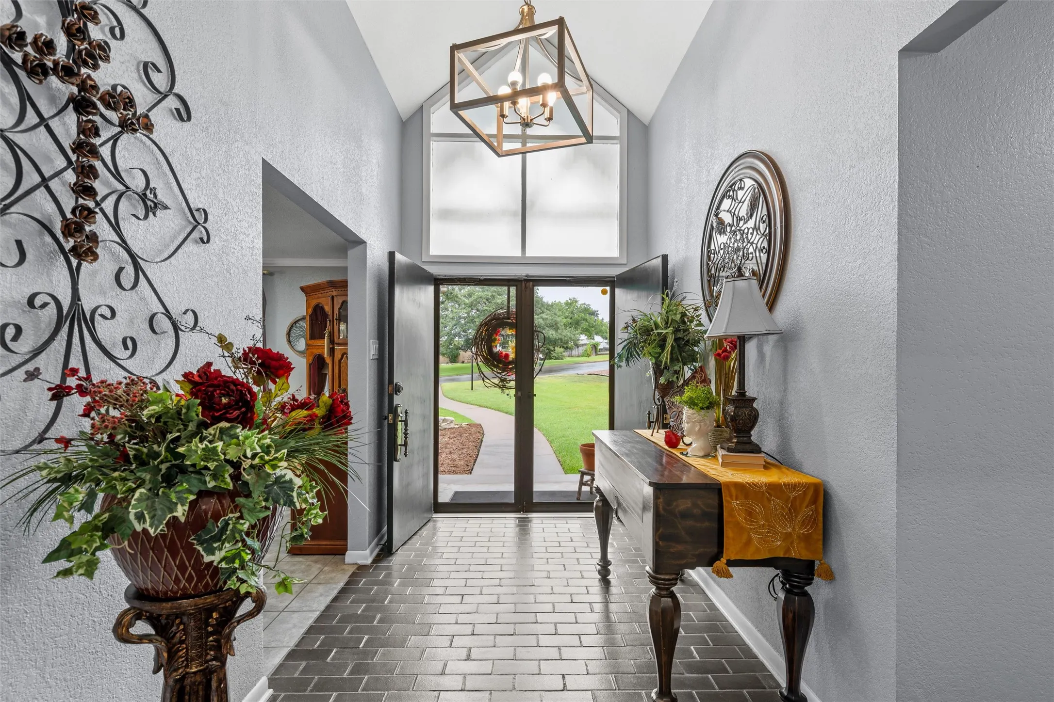 Vaulted entryway with transom window, double entry doors, wood-finish flooring, and a decorative overhead light fixture