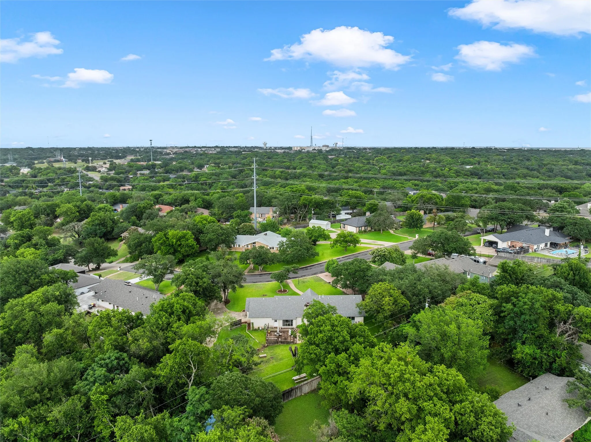 Expansive aerial perspective showcasing a residential neighborhood with abundant mature trees and a clear blue sky
