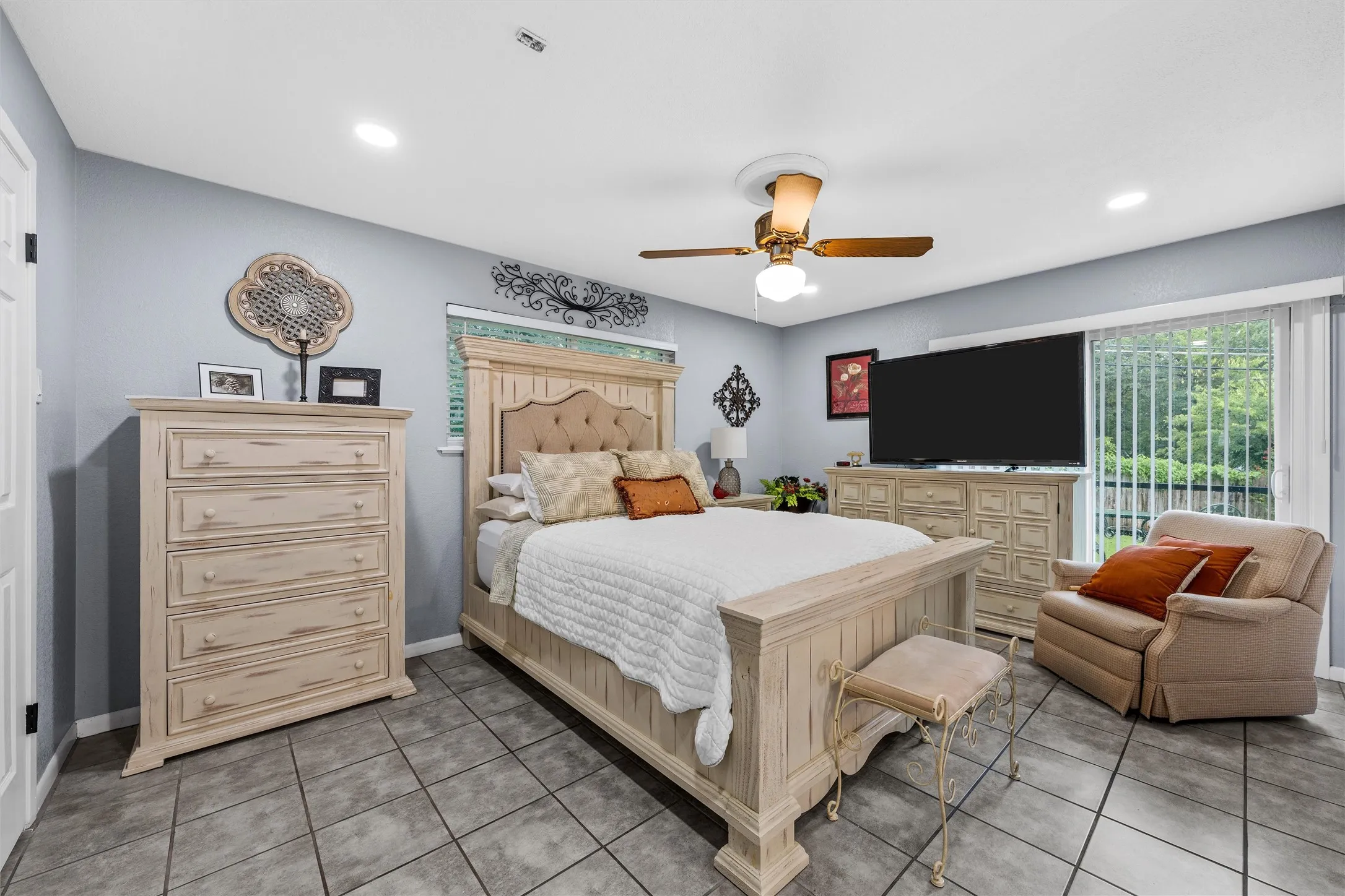 Spacious interior room featuring tile flooring, ceiling fan with integrated lighting, recessed lighting, and a sliding glass door providing exterior access