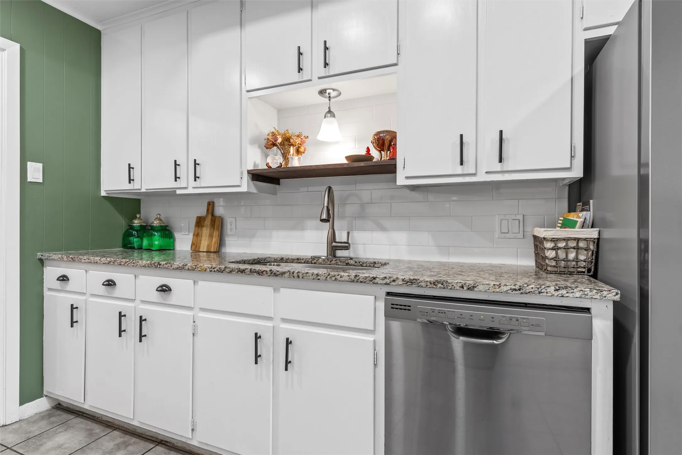 Kitchen featuring white cabinetry with matte black hardware, stone countertops, and a subway tile backsplash