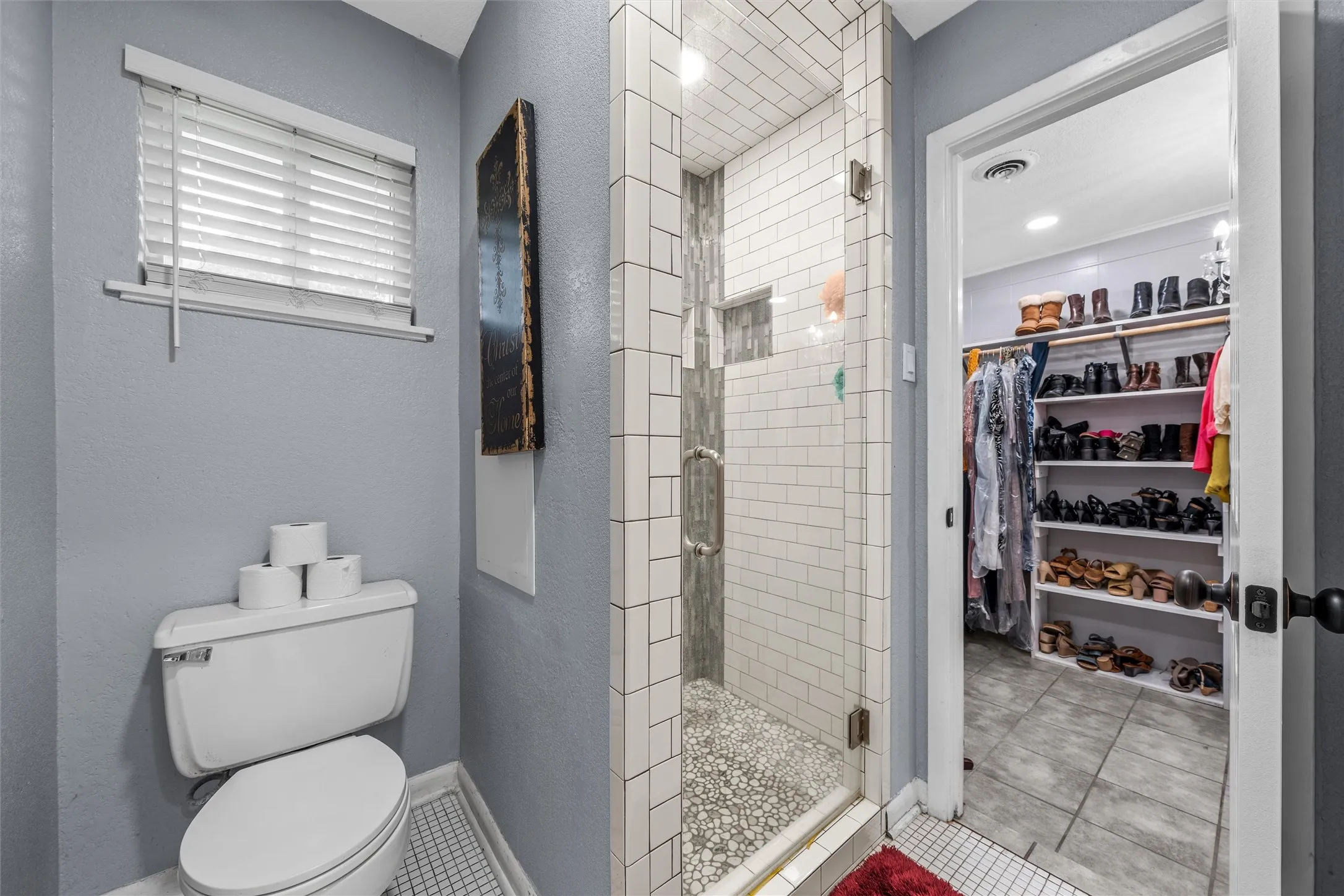 Walk-in shower with pebble floor and subway tile surround, clear glass enclosure, and recessed lighting