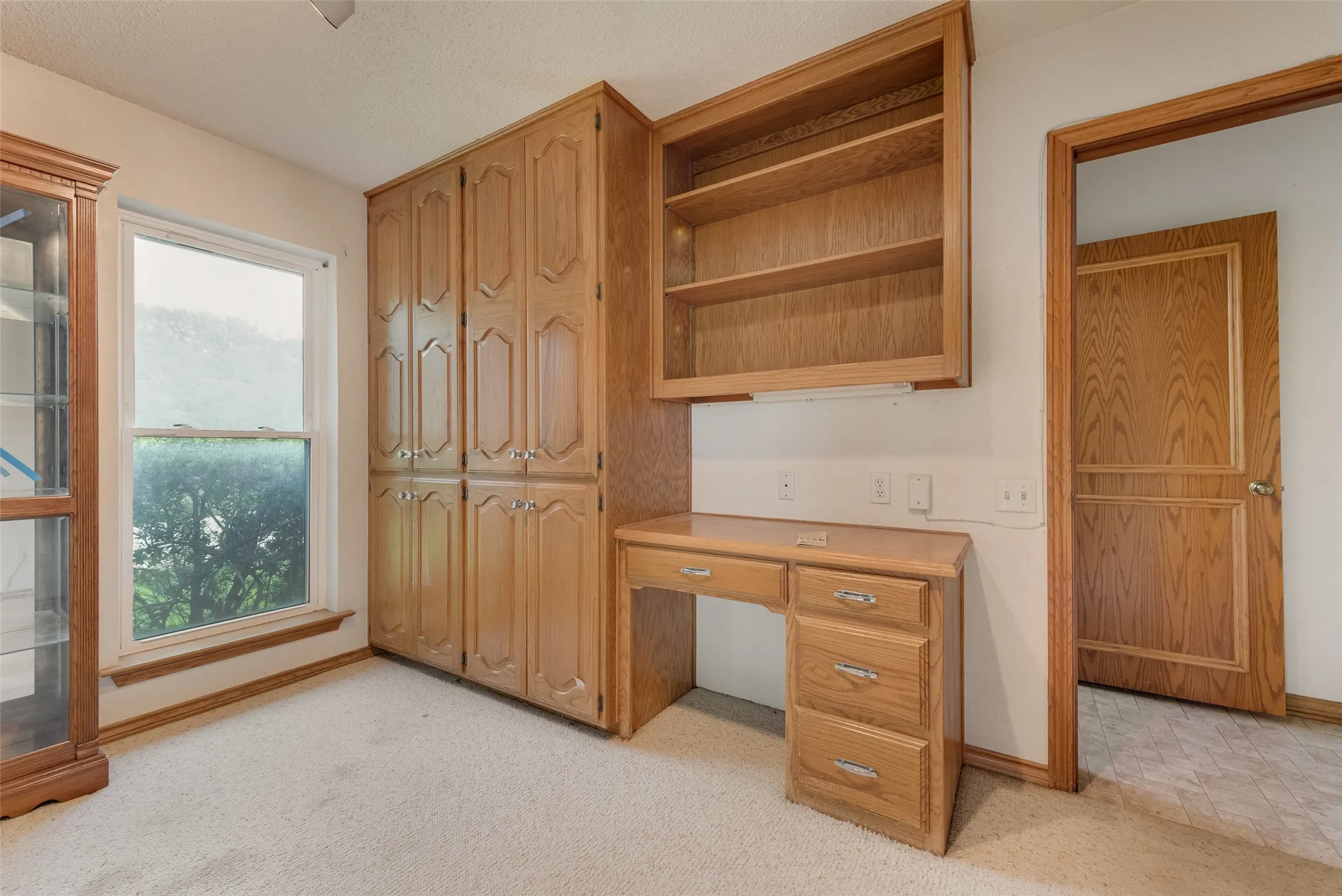 Built-in wood cabinetry, integrated desk, and shelving provide ample storage
