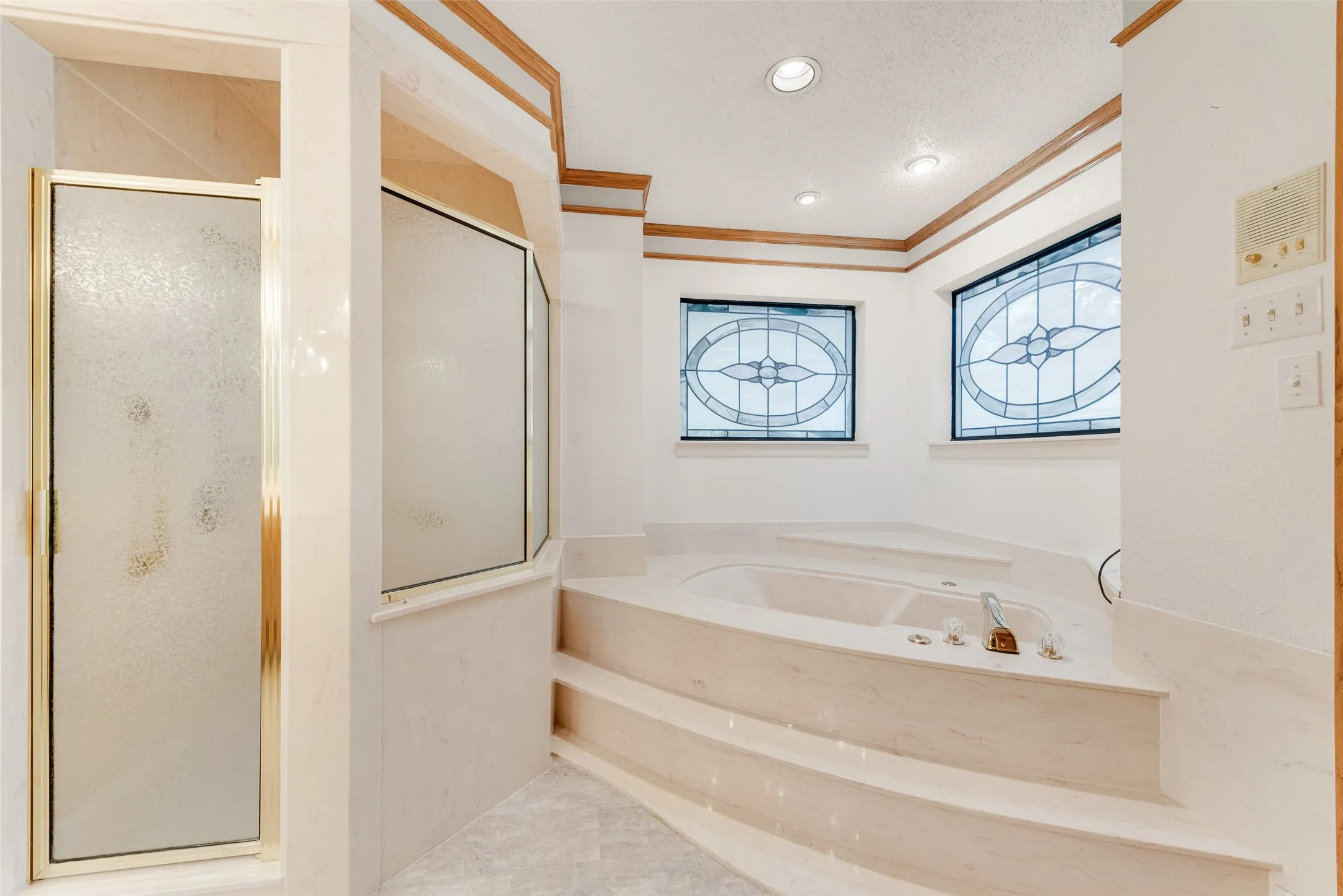 Soaking tub with integrated steps, framed by two decorative stained-glass windows