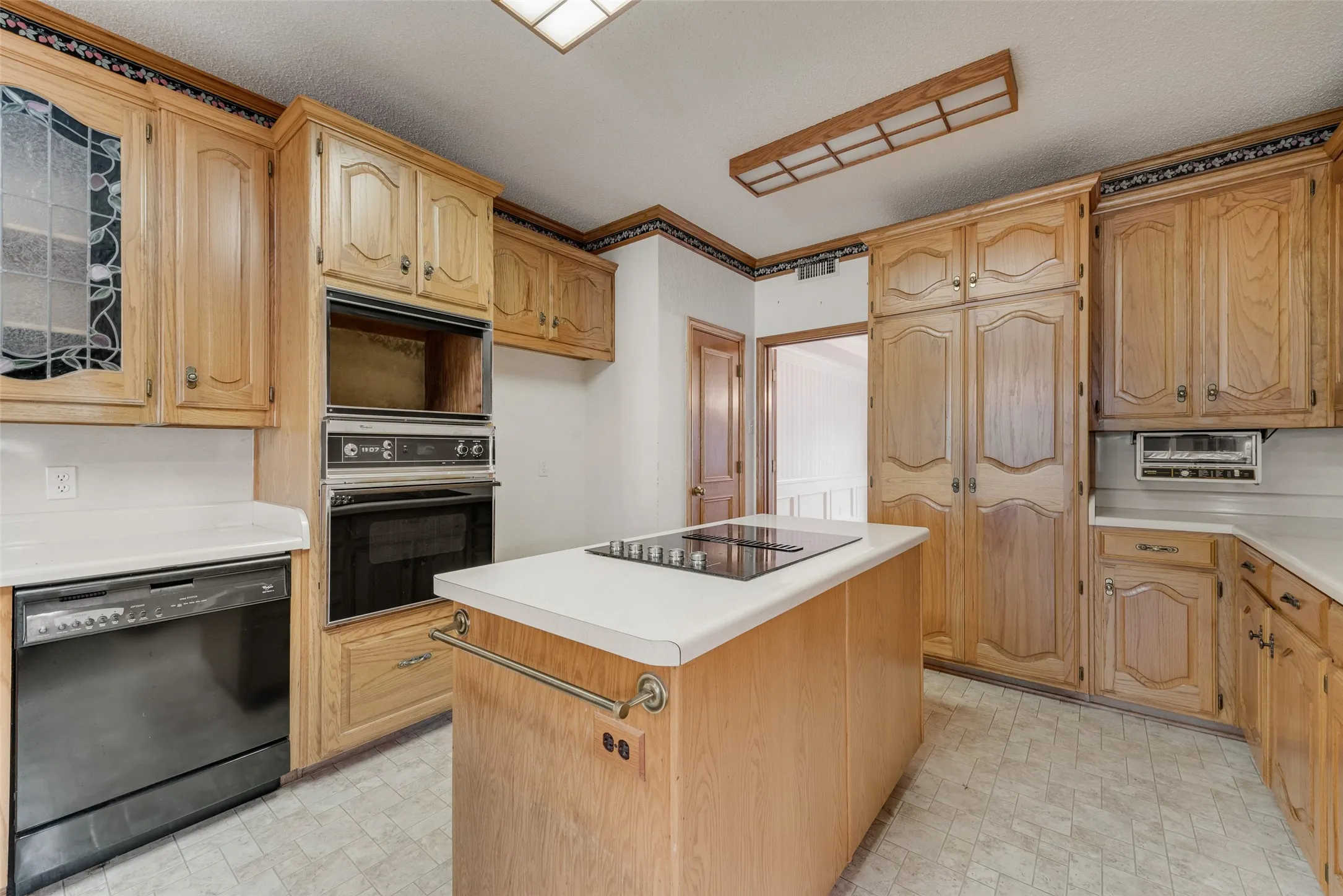 Kitchen featuring wood-finish cabinetry, white countertops, and a central island with an integrated cooktop