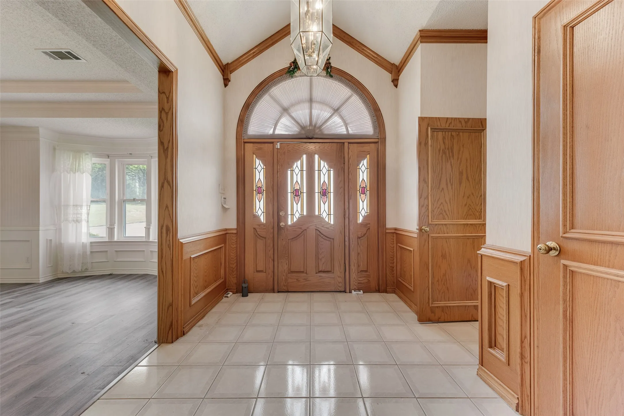 Grand entryway featuring a double door with decorative glass inserts and an arched transom window