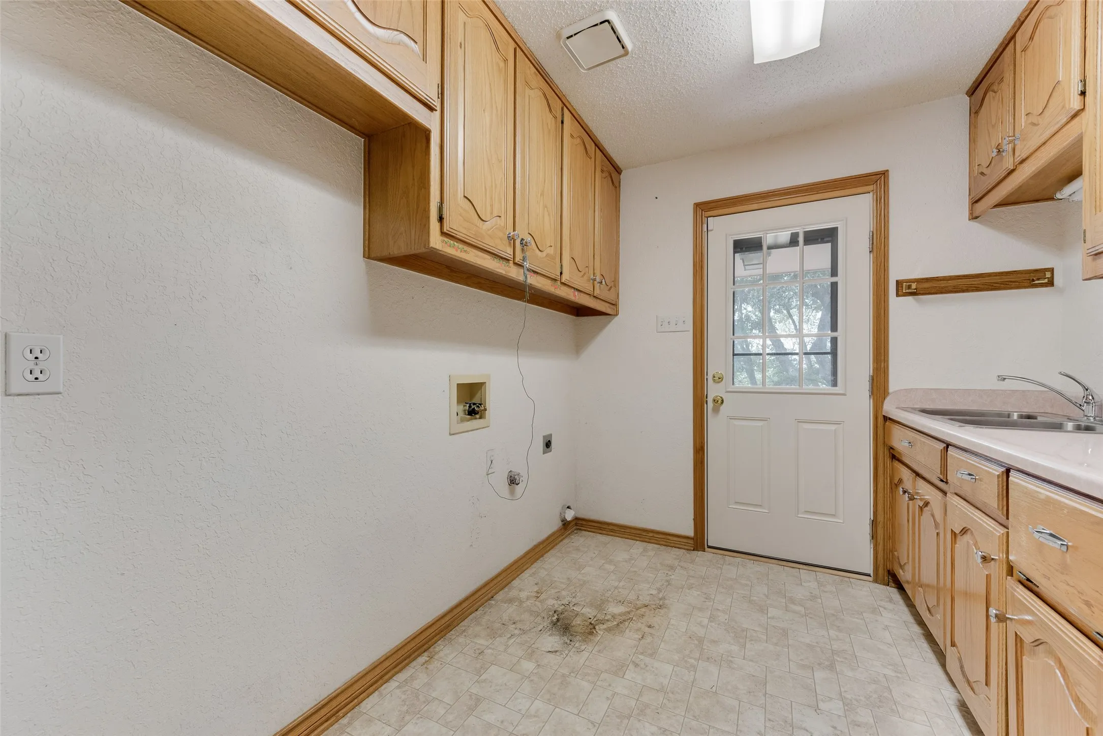 Utility room featuring wood cabinetry, white walls, and a light-colored vinyl floor
