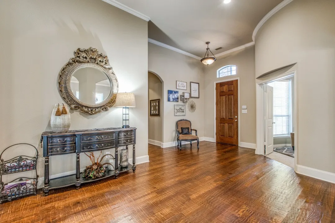 Spacious entry featuring wood-finish flooring, a paneled front door with an arched transom, and crown molding