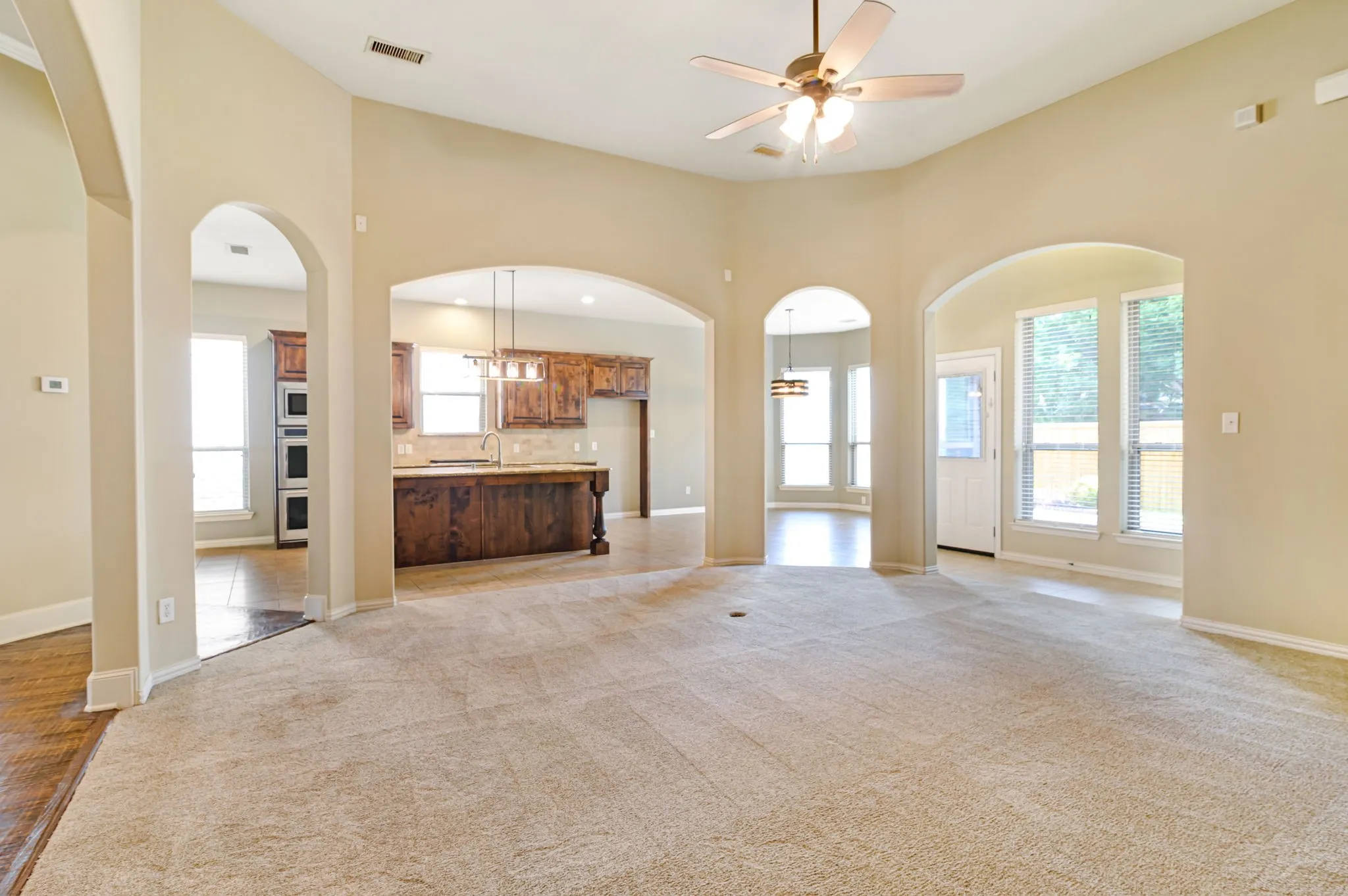 Carpeted living area with vaulted ceiling and ceiling fan