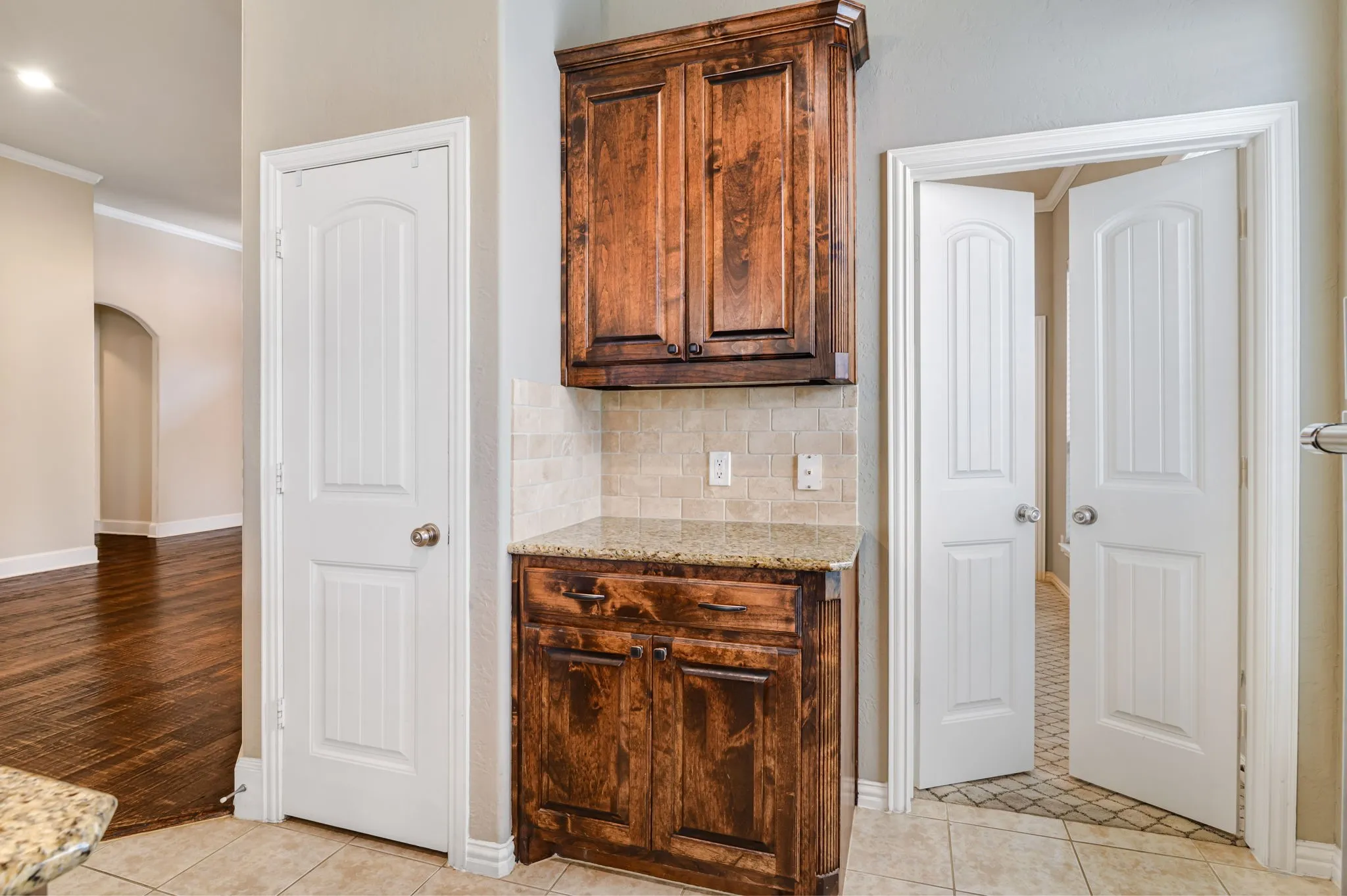 Built-in cabinetry with granite countertop, tiled backsplash, and wood-finish doors