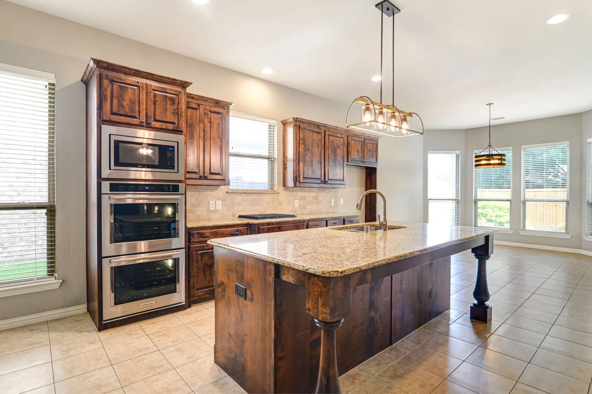 Kitchen featuring an expansive island with a stone-finish countertop and an undermount sink with a gooseneck faucet