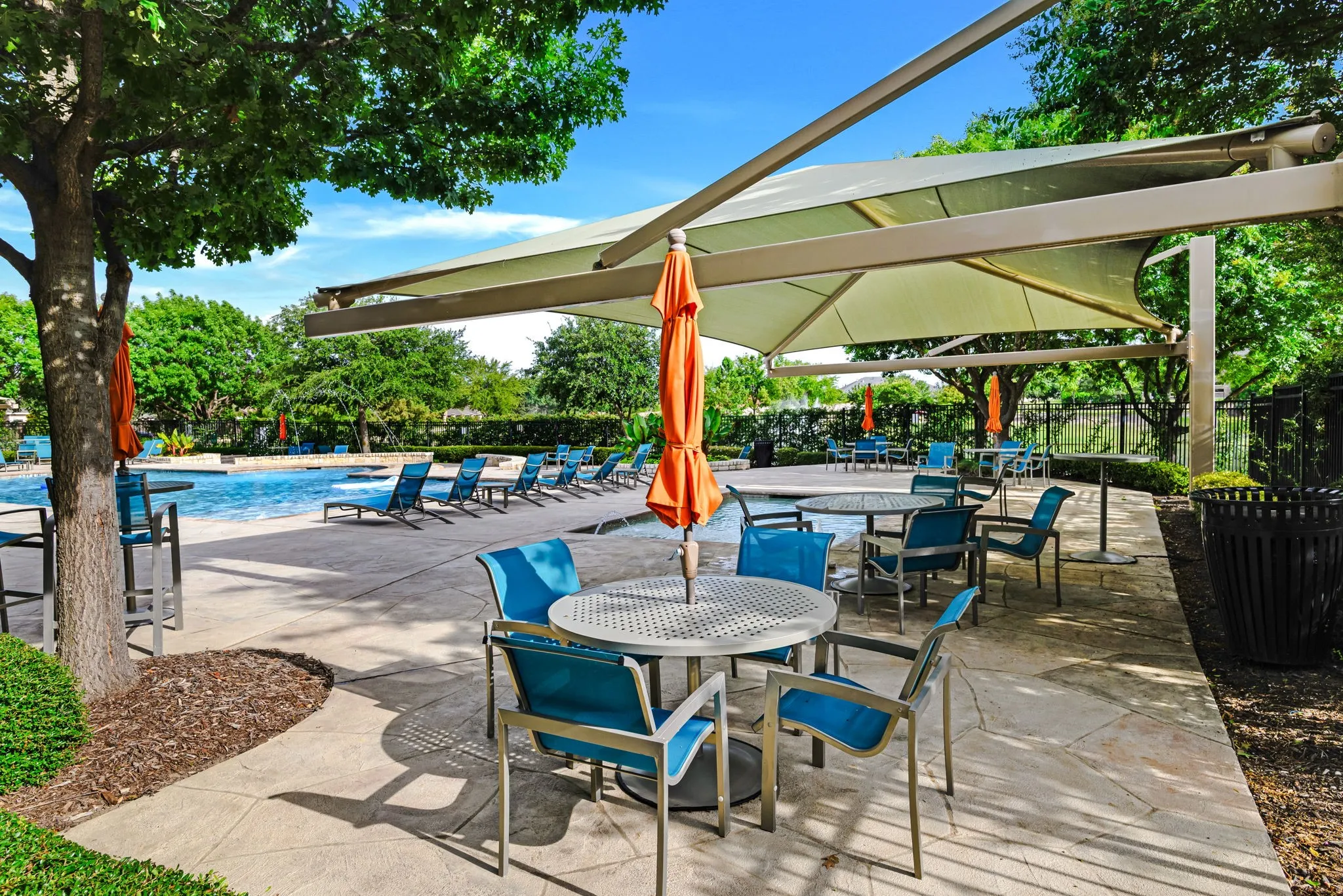 Expansive outdoor recreational area featuring a large swimming pool, surrounding patio, and multiple shade structures