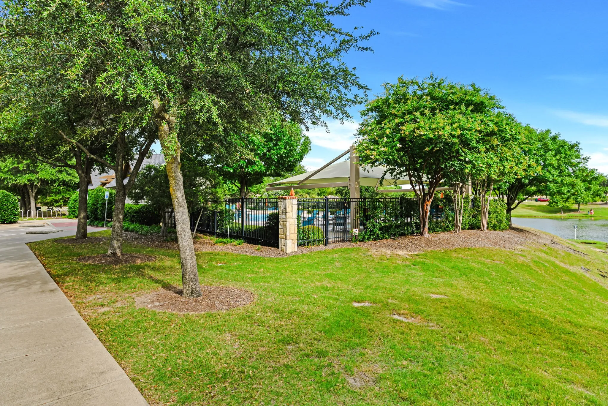 Manicured green space featuring mature trees and a paved walkway