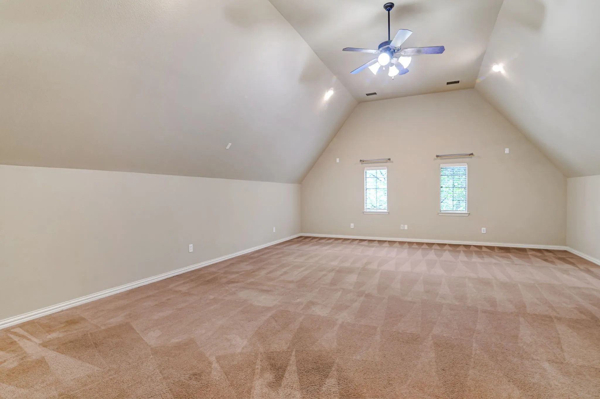 Spacious room featuring vaulted ceilings, recessed lighting, and a ceiling fan with light fixture