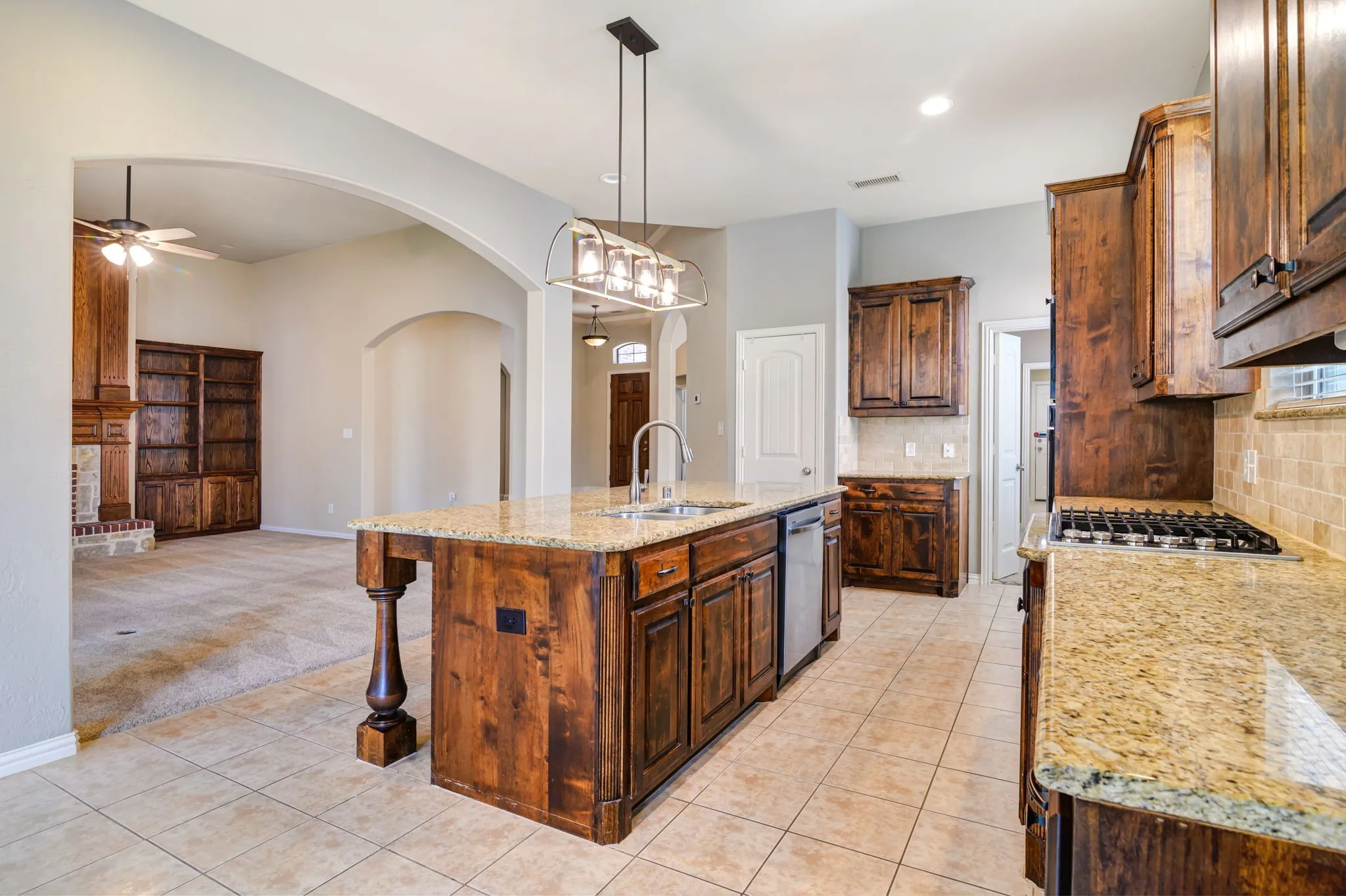 Kitchen with wood cabinetry, granite countertops, and tile flooring
