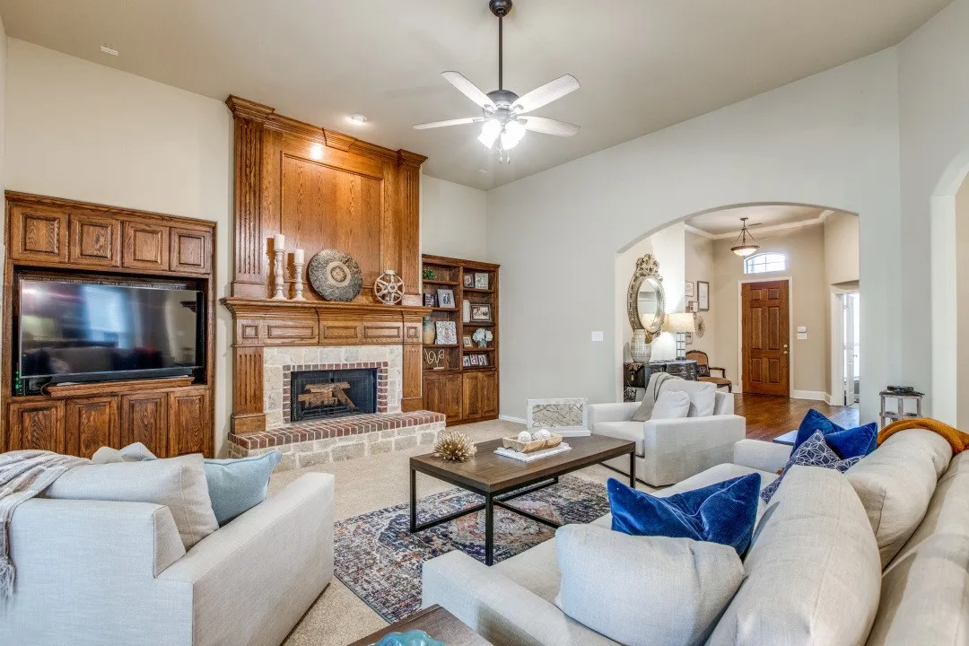 Living area featuring a floor-to-ceiling wood-paneled fireplace surround with a stone hearth, built-in media cabinetry, vaulted ceilings, and an arched entry