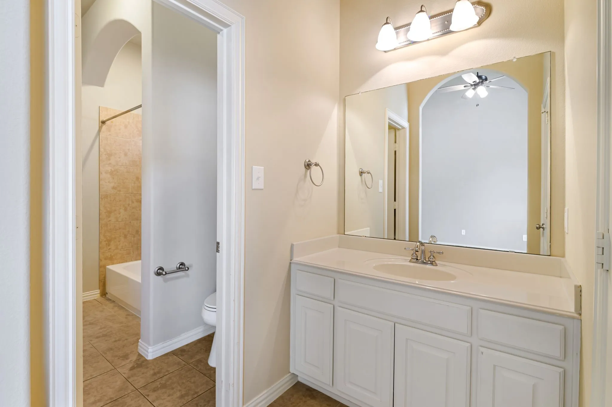 Bathroom vanity featuring a white countertop with integrated sink, coordinating white cabinetry, and a large wall-mounted mirror