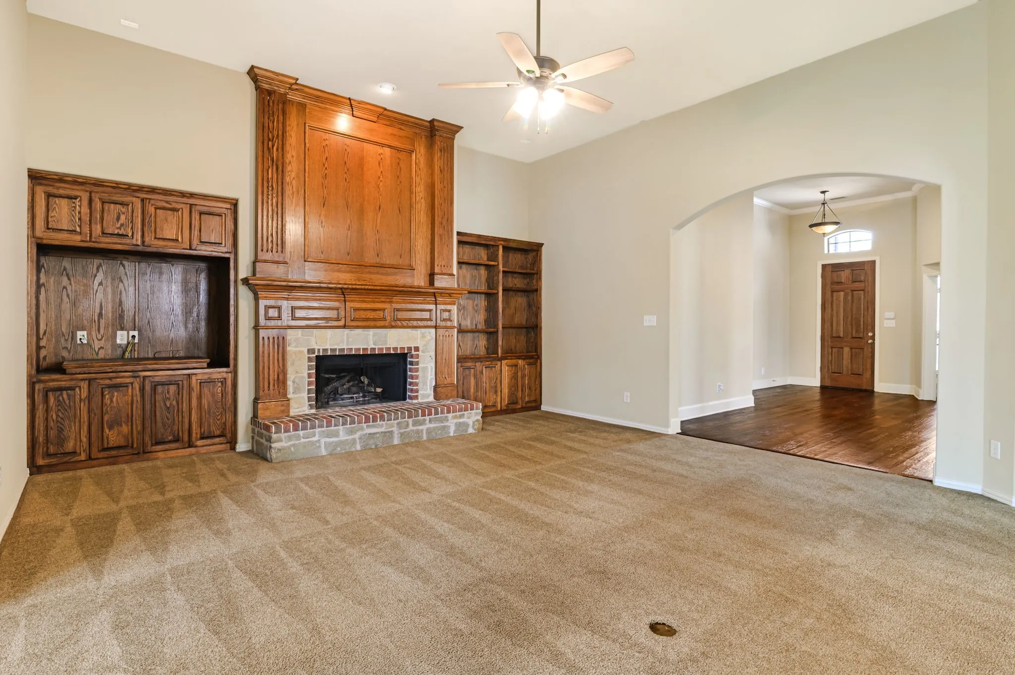 Living area featuring a floor-to-ceiling wood-paneled fireplace with a stone and brick surround