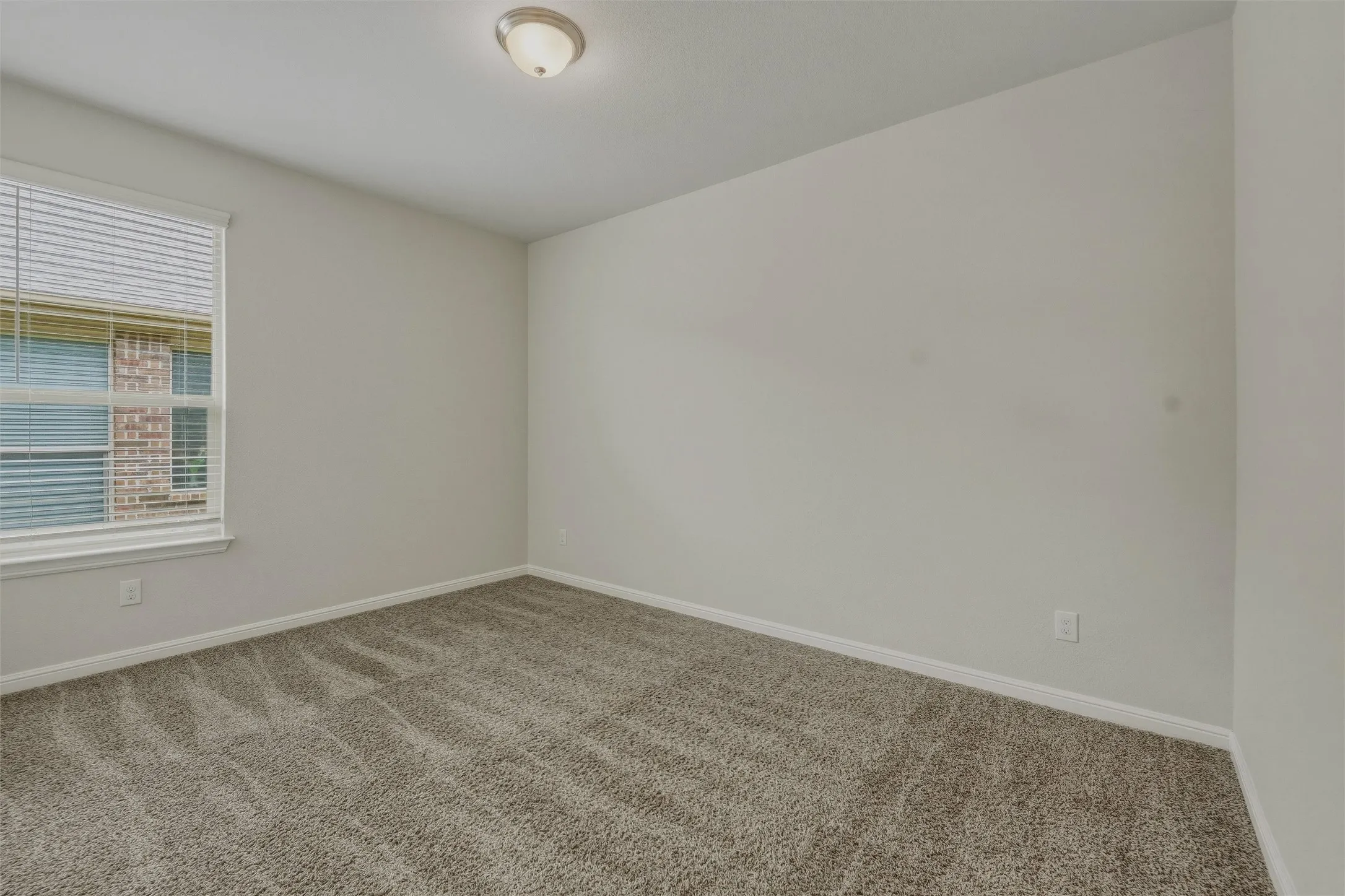 Carpeted interior space with a window featuring horizontal blinds