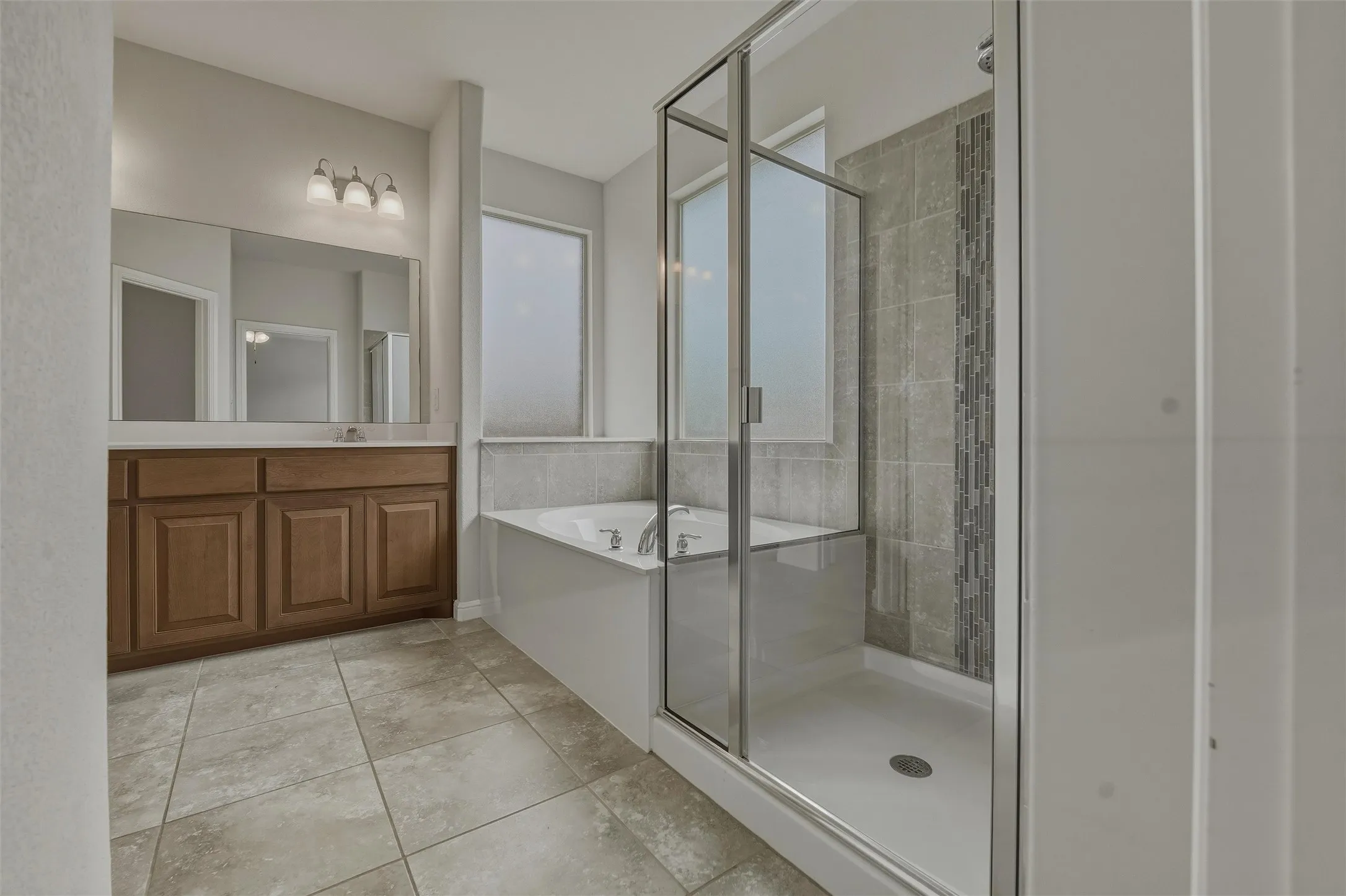 Bathroom featuring a glass-enclosed shower, a built-in bathtub, and a wood-finish vanity with a large mirror