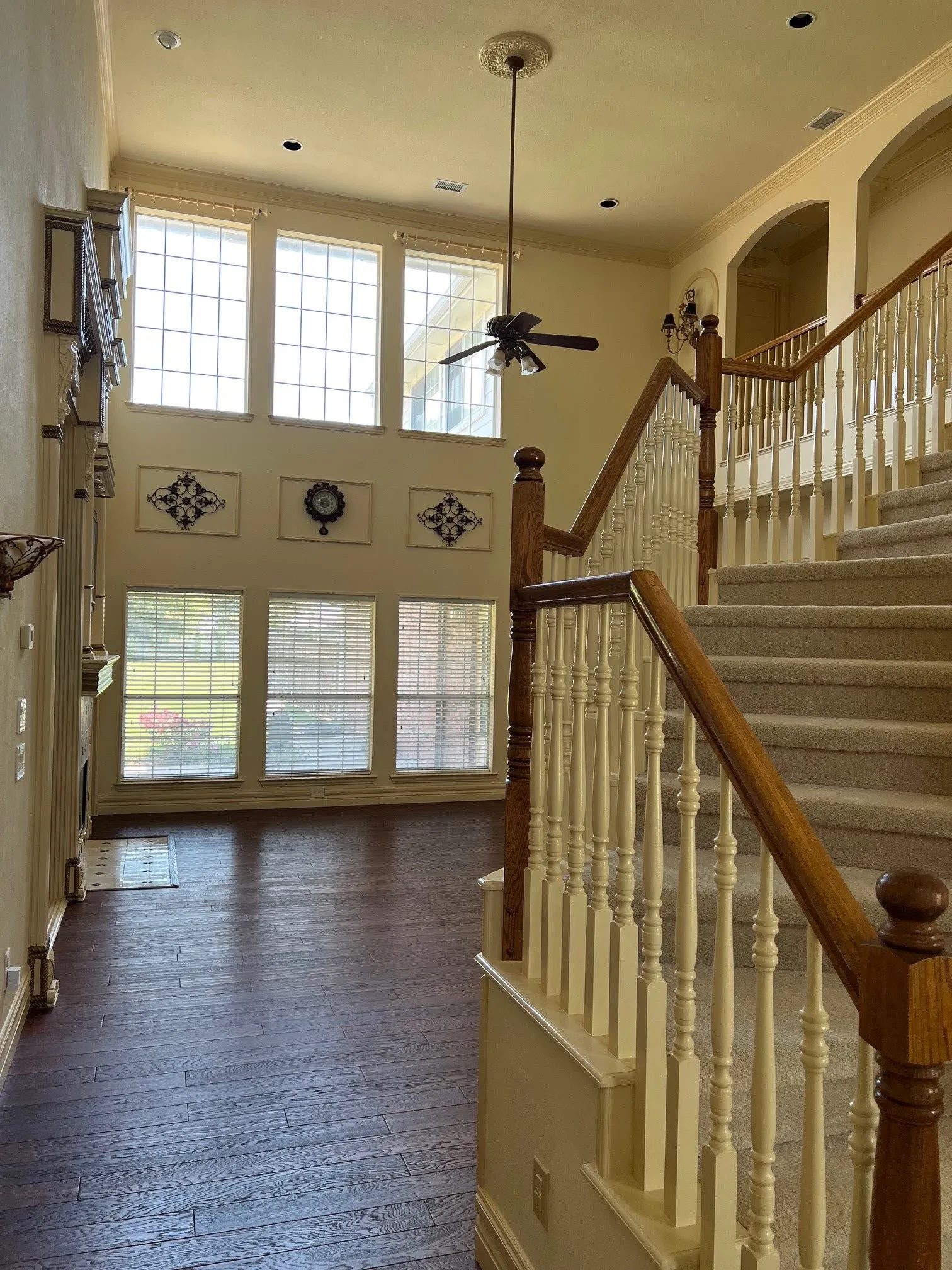Stairway featuring a high ceiling, wood-type flooring, crown molding, and ceiling fan