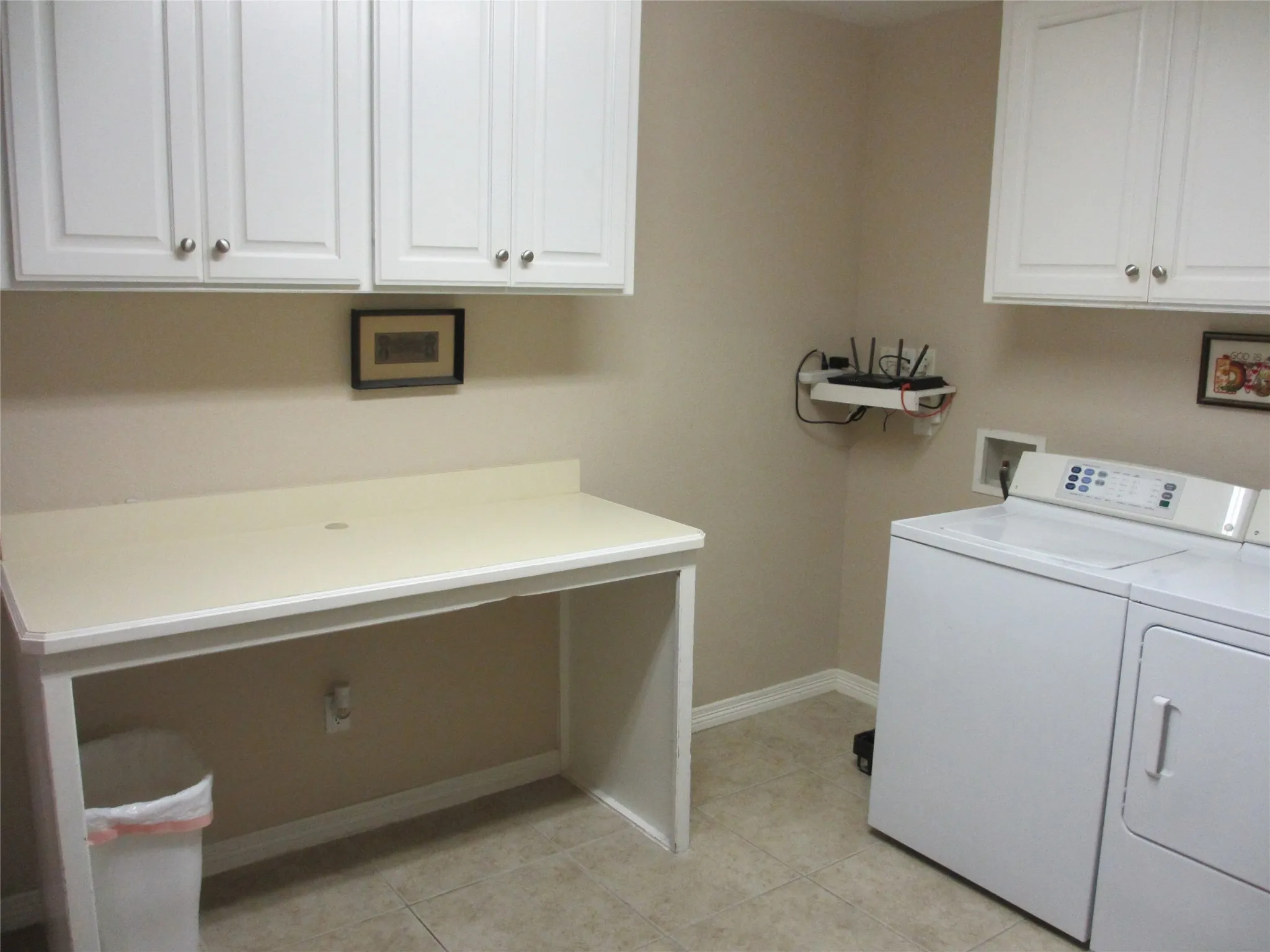 Laundry room with full size washer and dryer, lots of cabinets and a folding table