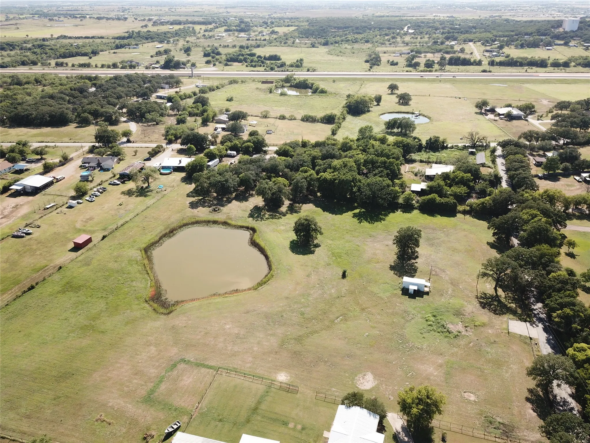 Eastern view of acreage featuring a large pond, mature trees, and Chisholm Tollway is the distance