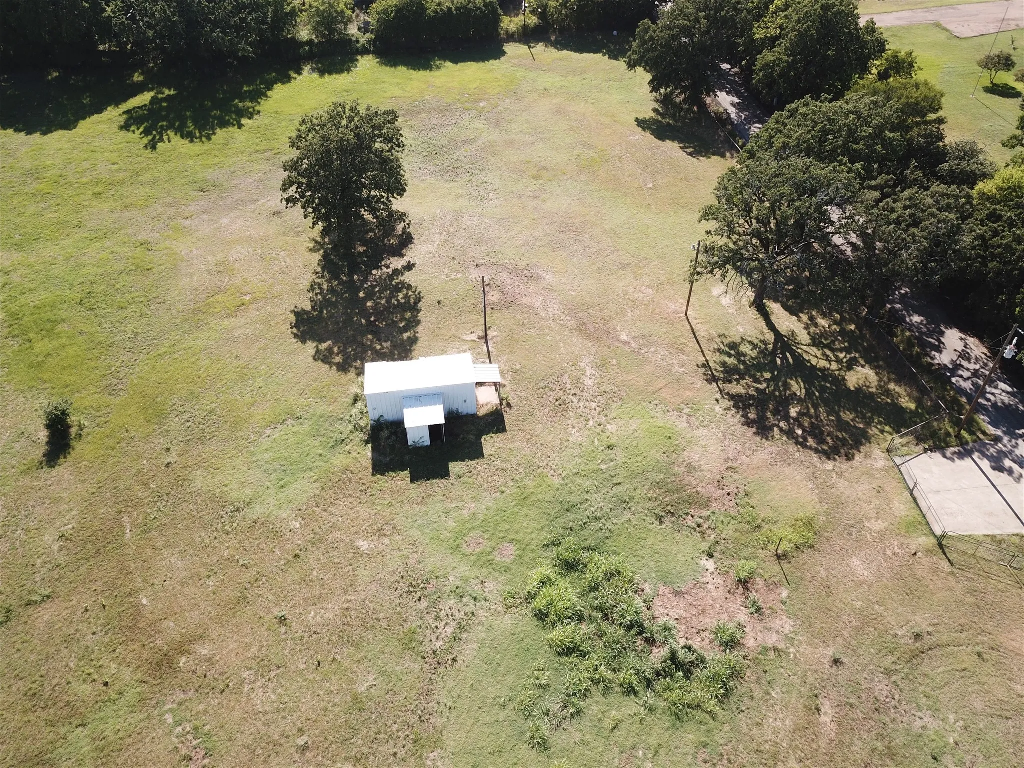 Expansive open land featuring a detached utility building with a white metal exterior