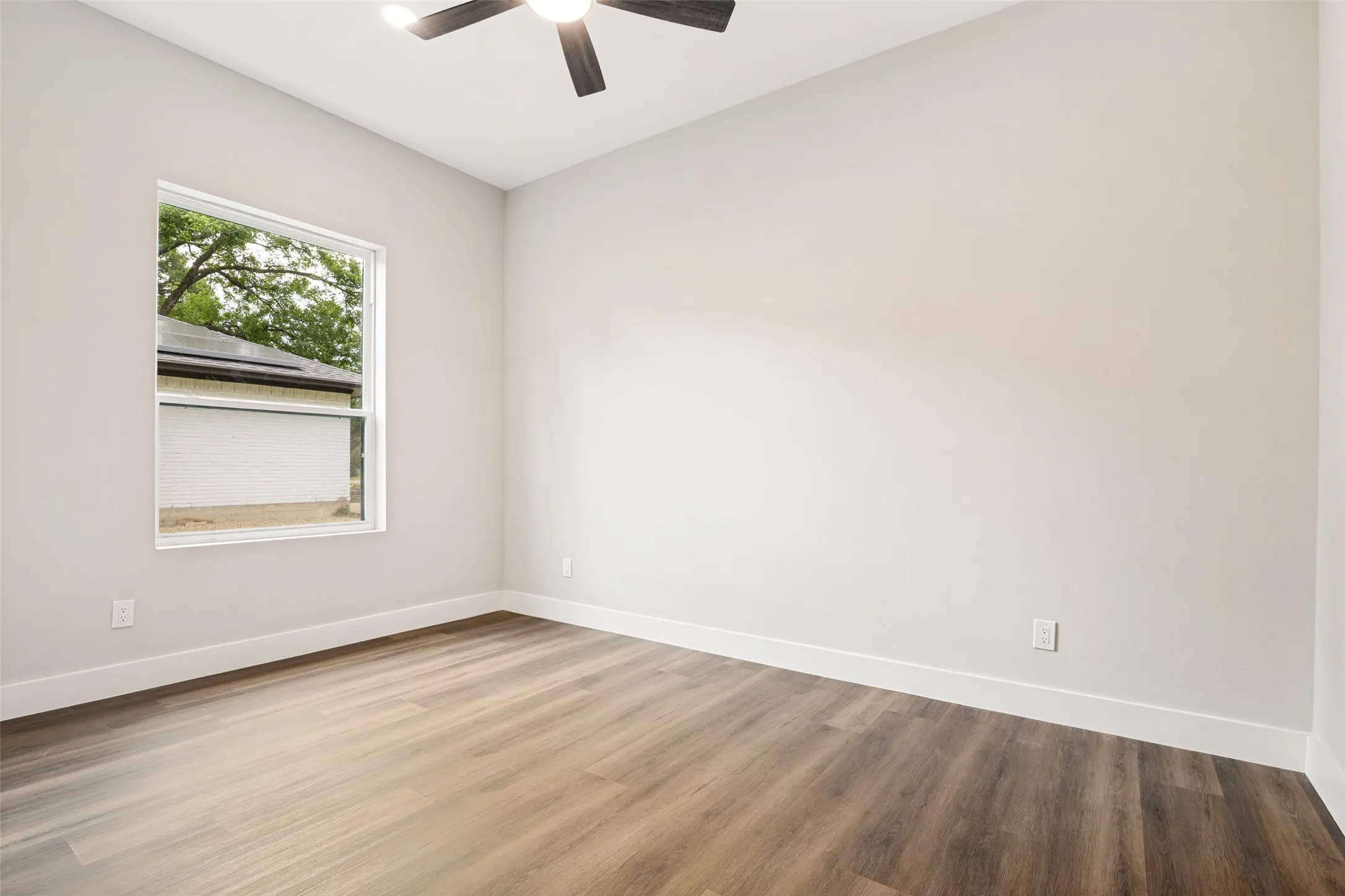 Bright interior space featuring wood-finish flooring, a contemporary ceiling fan, and a double-hung window with a classic white frame