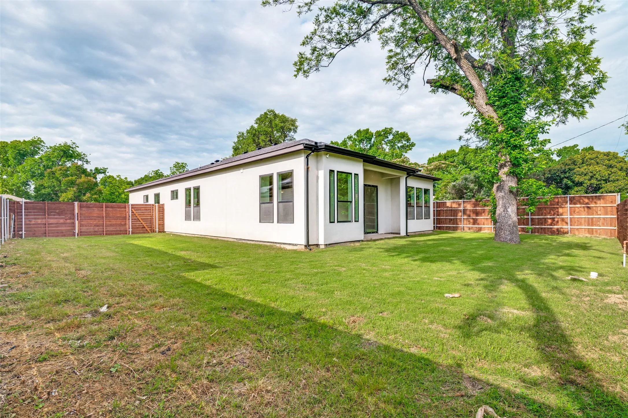 Expansive backyard featuring a lush lawn, privacy fencing, and mature trees